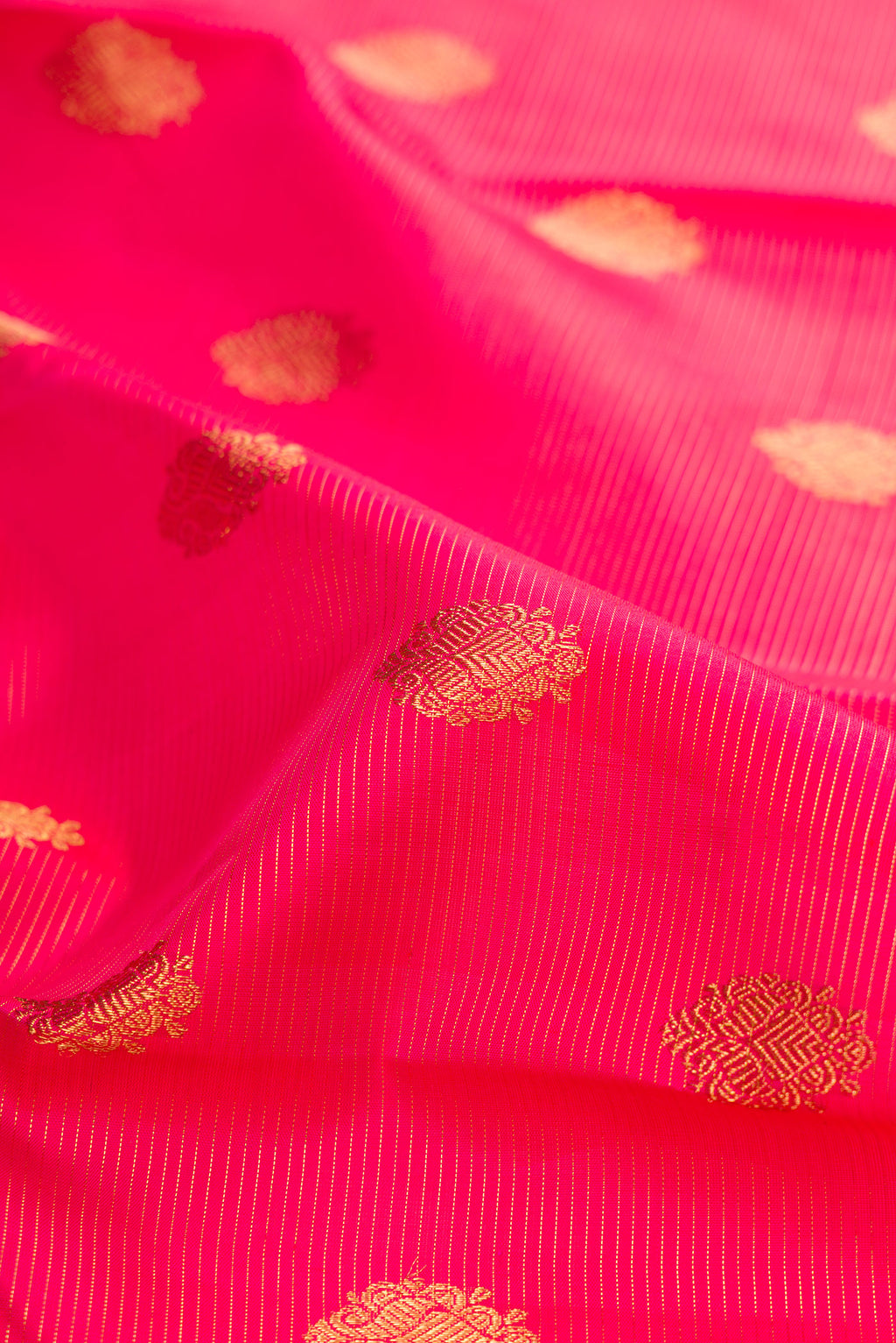 Close up of Pure Silk Pure Zari Dark Pink Kanjivaram Saree with Zari Butta on the body and Zari Border.  displaying folds