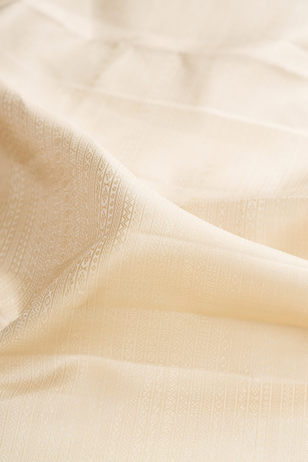 Close up of Cream Kanjivaram Silk Saree with Jacquard design on the body and Zari Border.  displaying folds