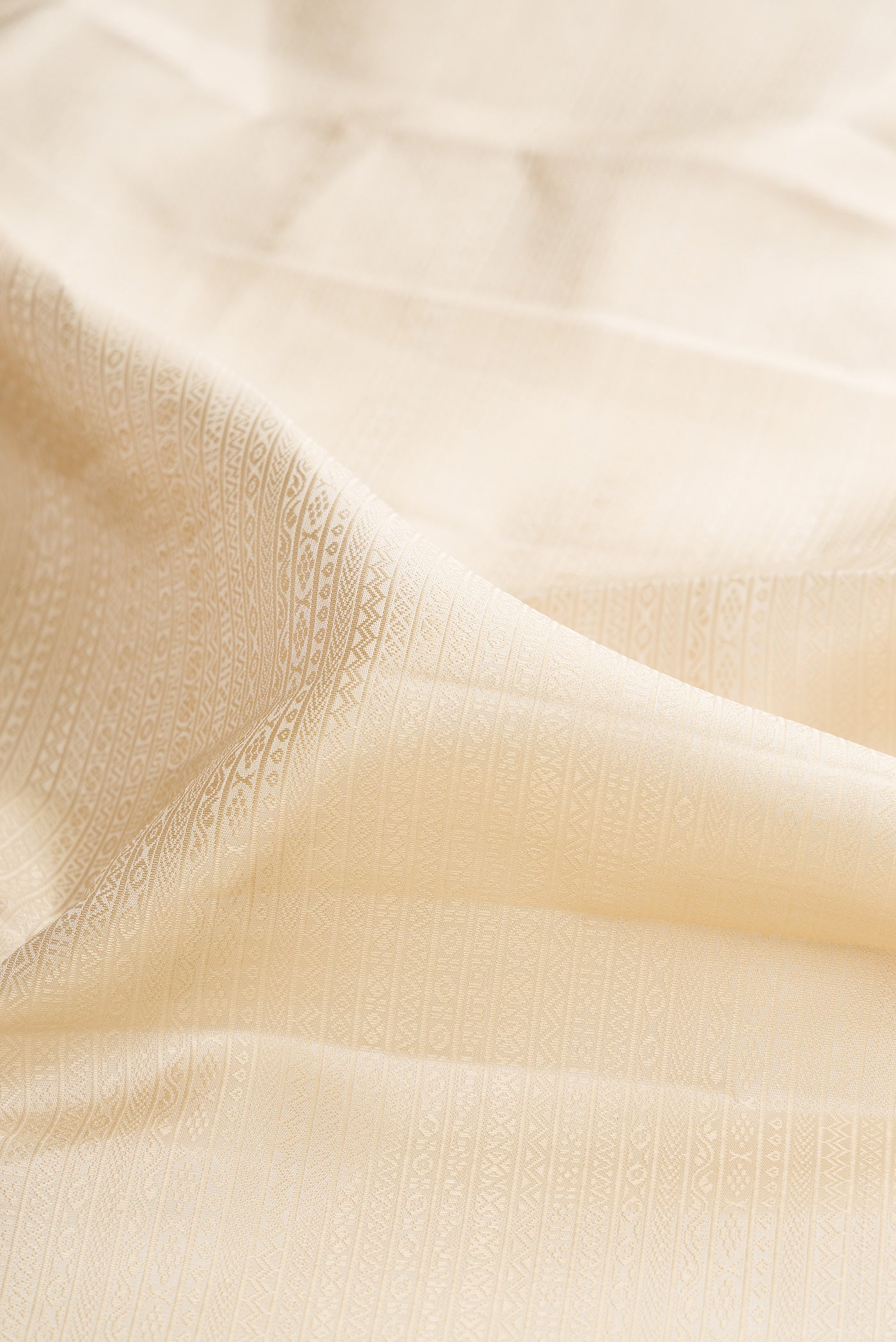Close up of Cream Kanjivaram Silk Saree with Jacquard design on the body and Zari Border.  displaying folds
