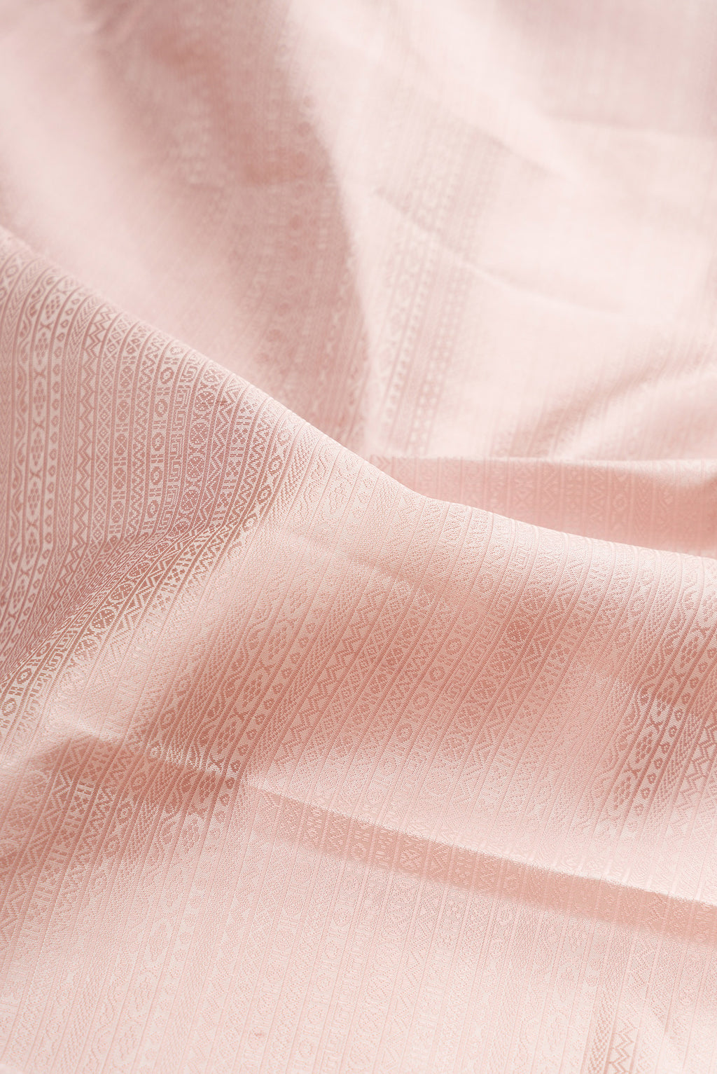 Close up of Rose Gold Kanjivaram Silk Saree with Jacquard design on the body and Zari Border.  displaying folds