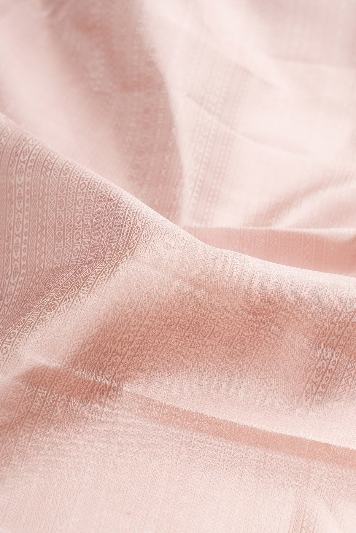 Close up of Rose Gold Kanjivaram Silk Saree with Jacquard design on the body and Zari Border.  displaying folds