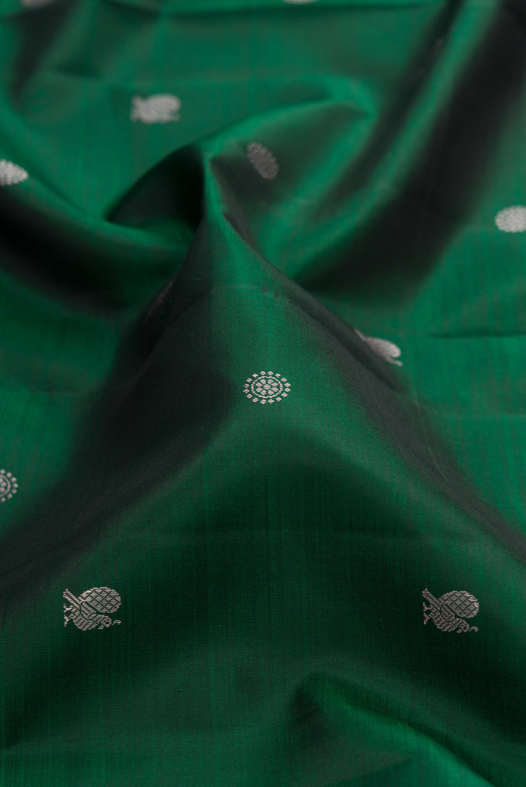 Close up of Pure Silk Bottle Green Kanchipuram Saree with Thread Butta on the body and Thread Border.  displaying folds