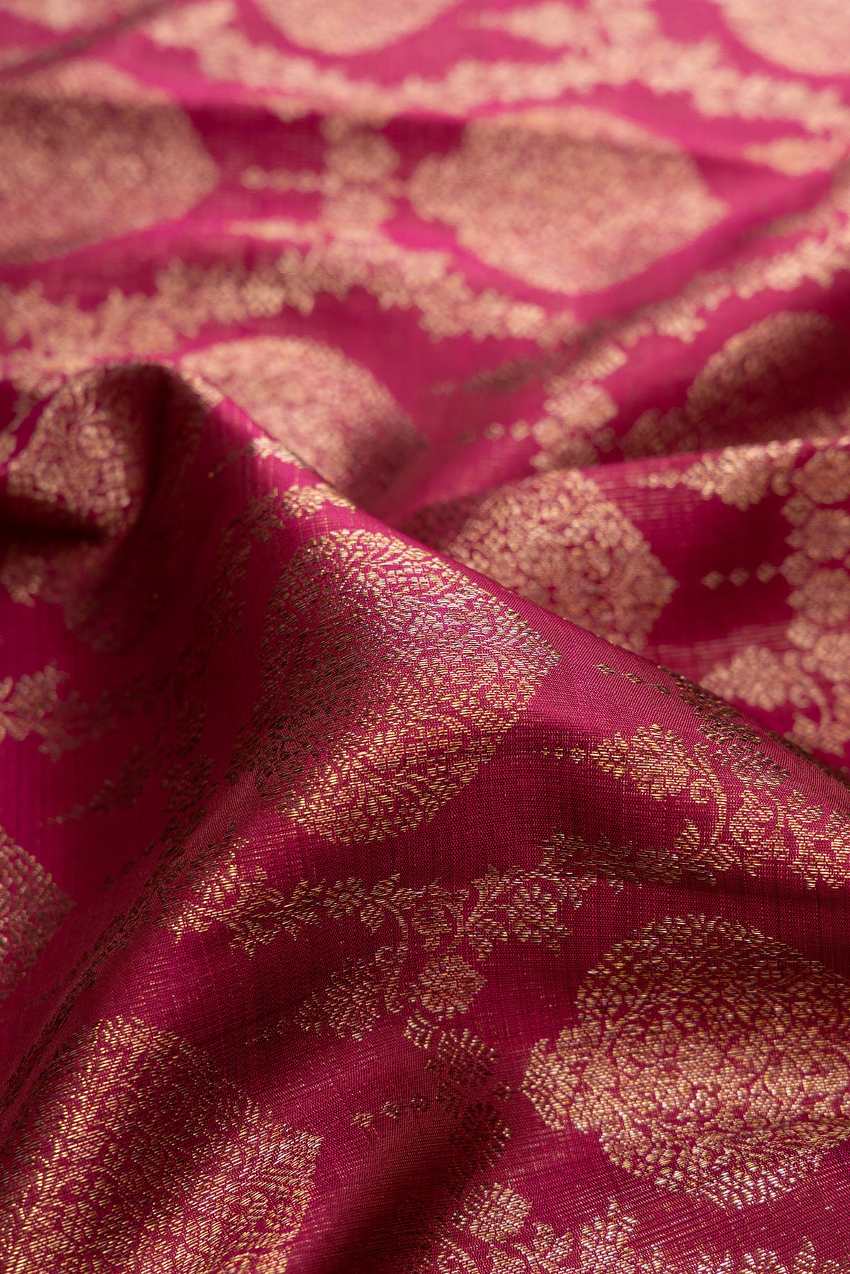 Close up of Pure Silk Magenta Kanchipuram Saree with Zari Brocade on the body and Zari Border.  displaying folds