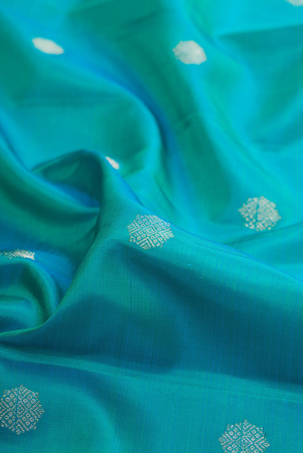 Close up of Pure Silk Peacock Blue Kanchipuram Saree with Zari Butta on the body and Temple Border.  displaying folds