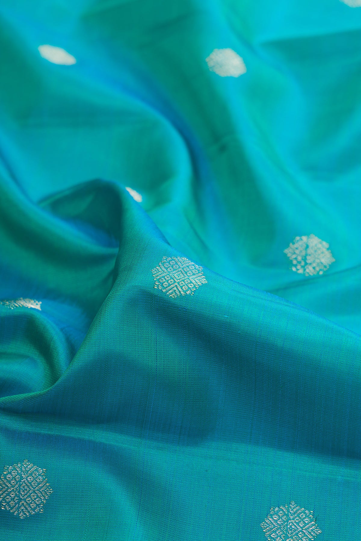 Close up of Pure Silk Peacock Blue Kanchipuram Saree with Zari Butta on the body and Temple Border.  displaying folds