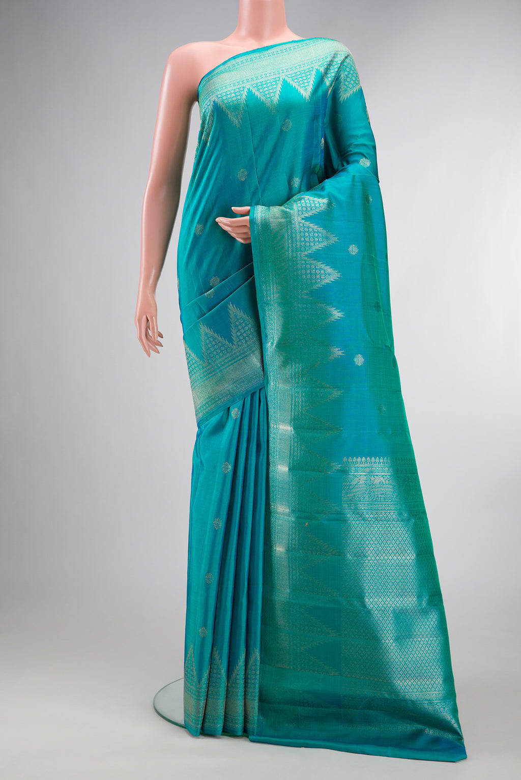 Pure Silk Peacock Blue Kanchipuram Saree with Zari Butta on the body and Temple Border.  displayed on a mannequin
