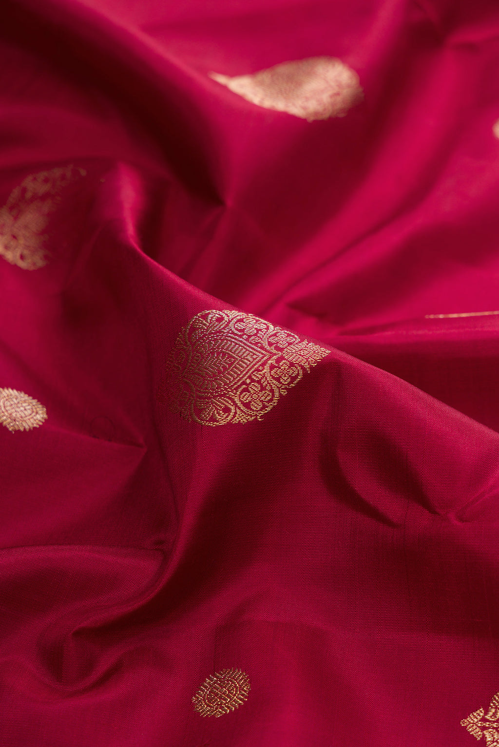 Close up of Pure Silk Maroon Kanjivaram Saree with Zari Butta on the body and Zari Border.  displaying folds