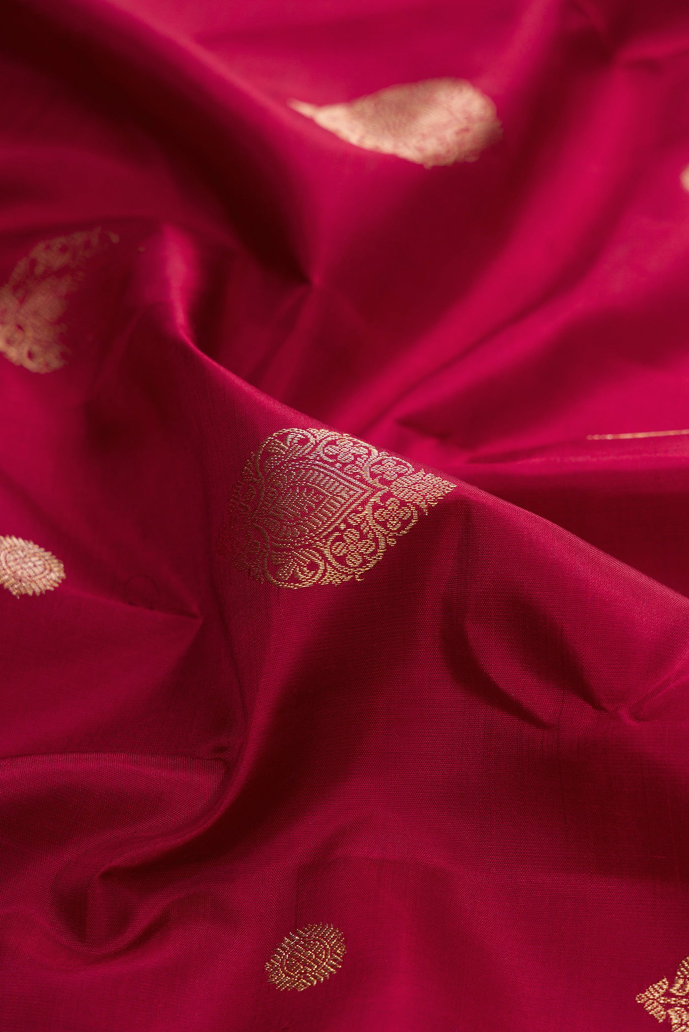 Close up of Pure Silk Maroon Kanjivaram Saree with Zari Butta on the body and Zari Border.  displaying folds