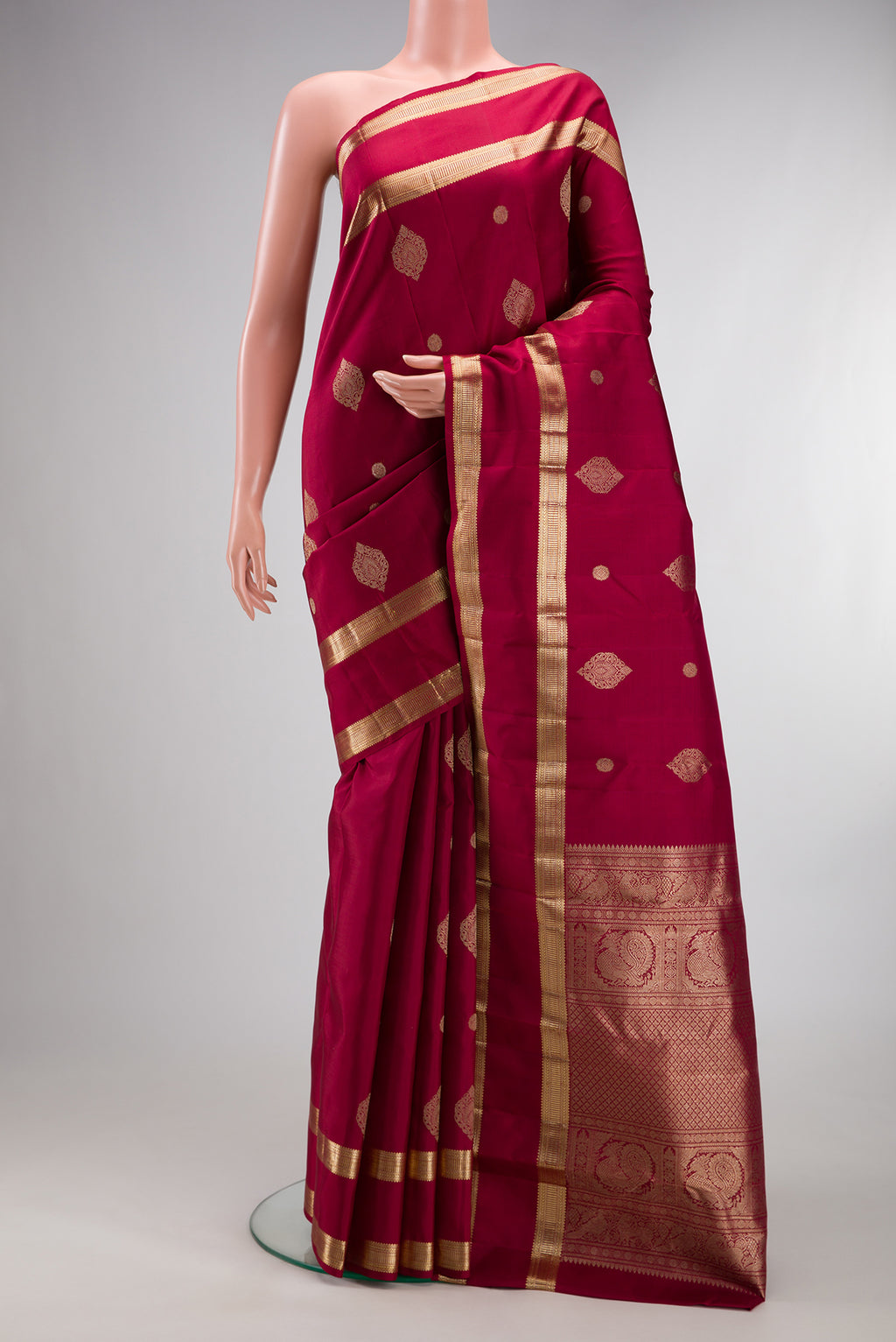 Pure Silk Maroon Kanjivaram Saree with Zari Butta on the body and Zari Border.  displayed on a mannequin
