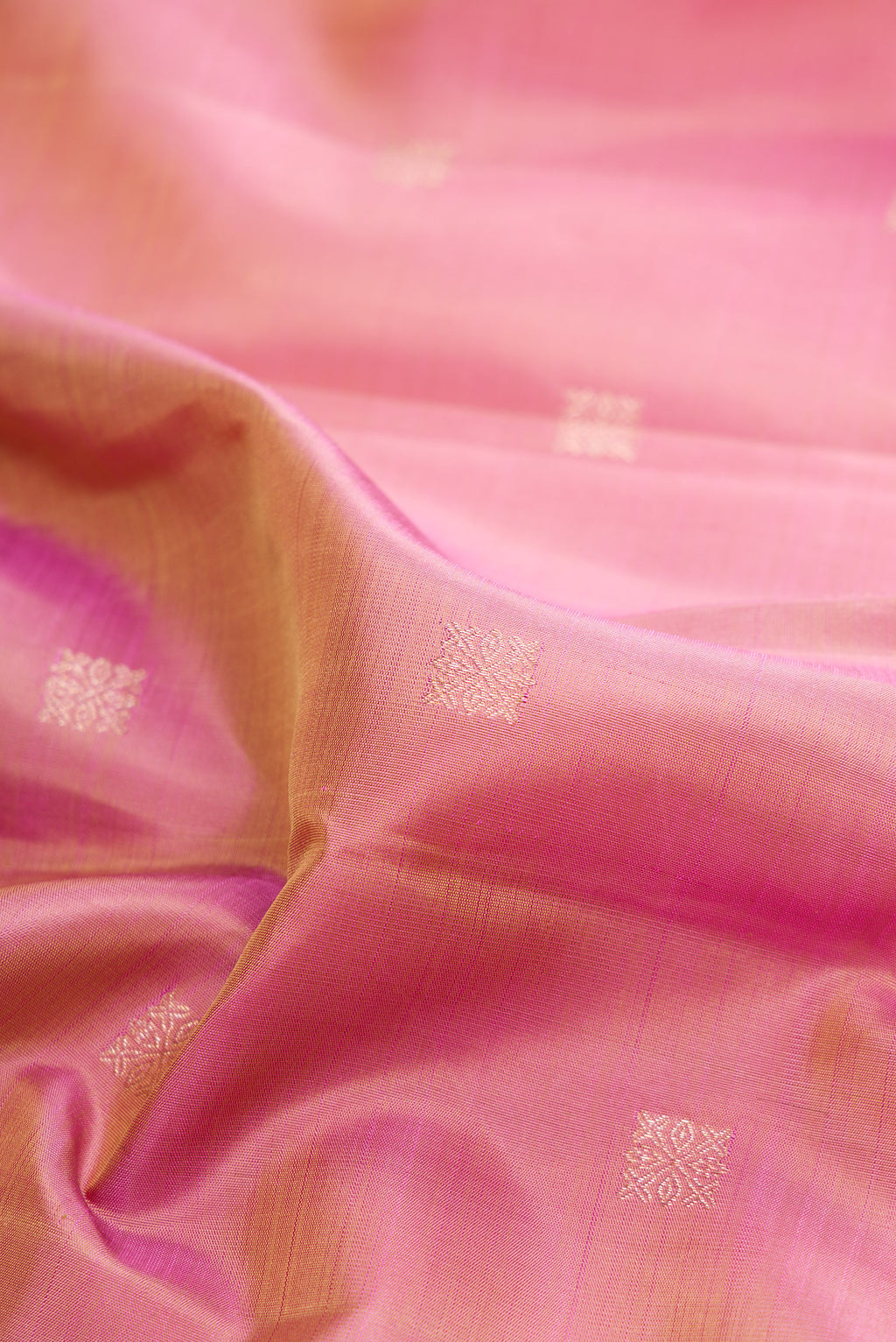 Close up of Pure Silk Rose Gold Dual Tone Kanjivaram Saree with Zari Butta on the body and Zari Border.  displaying folds