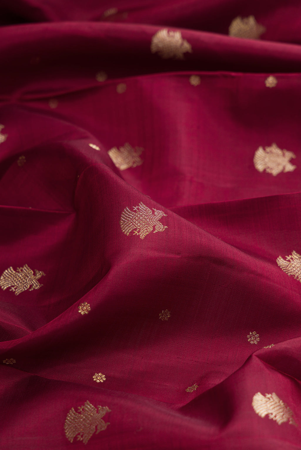 Close up of Pure Silk Maroon Kanjivaram Saree with Zari Butta on the body and Zari Border.  displaying folds