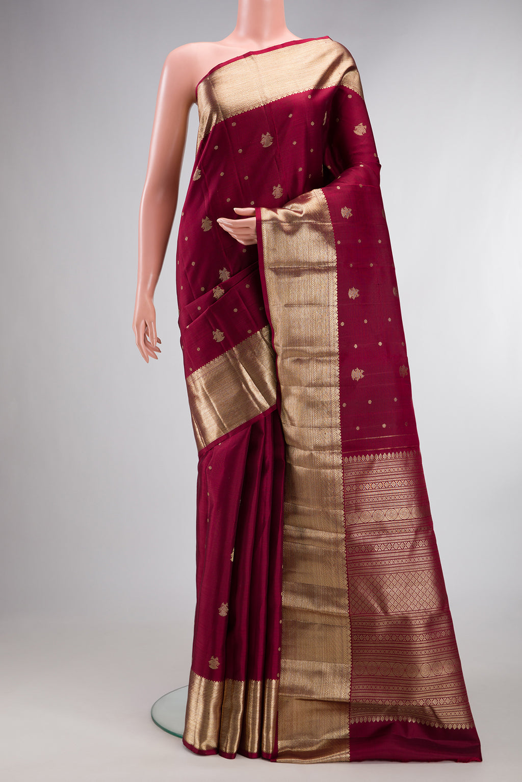 Pure Silk Maroon Kanjivaram Saree with Zari Butta on the body and Zari Border.  displayed on a mannequin