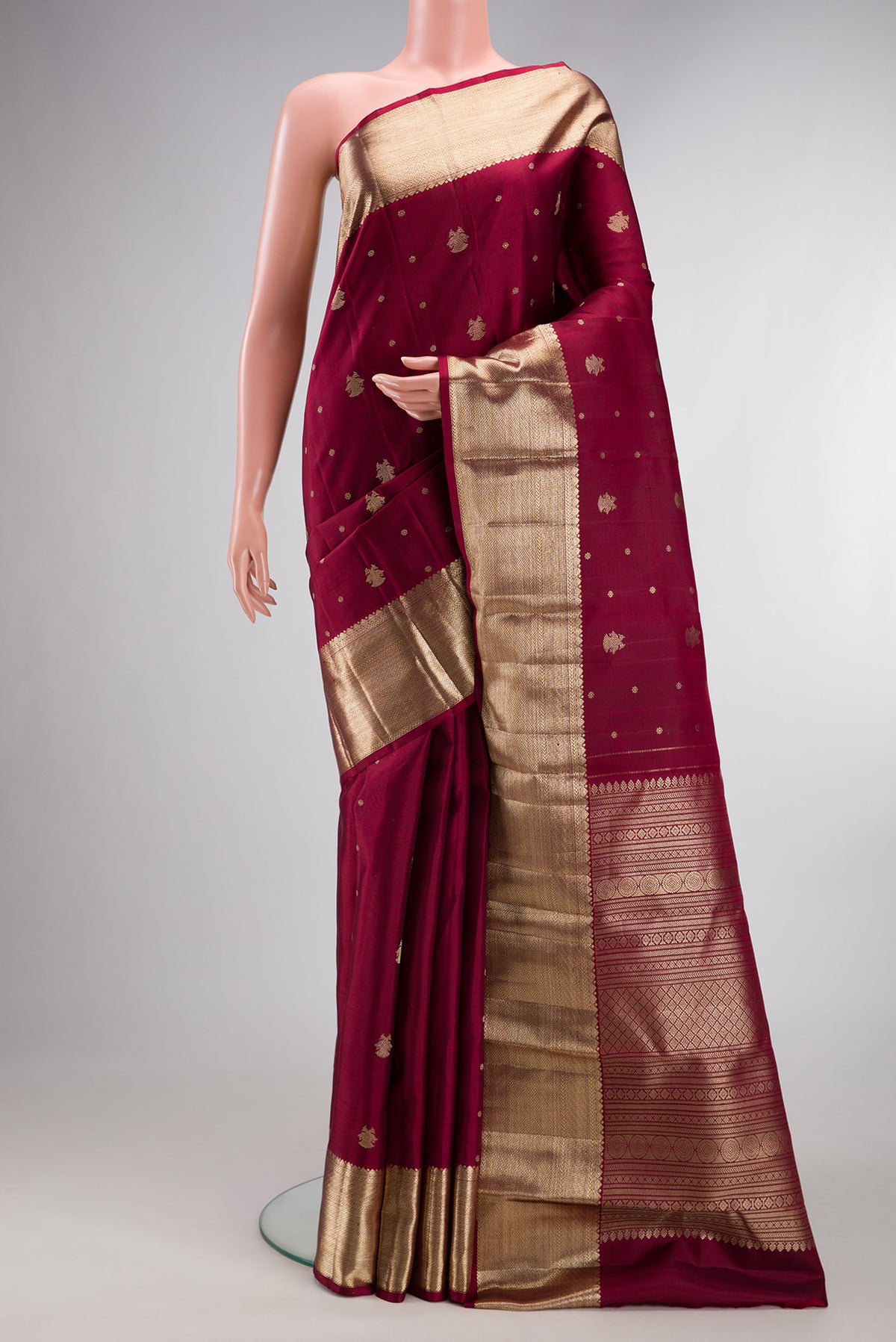 Pure Silk Maroon Kanjivaram Saree with Zari Butta on the body and Zari Border.  displayed on a mannequin