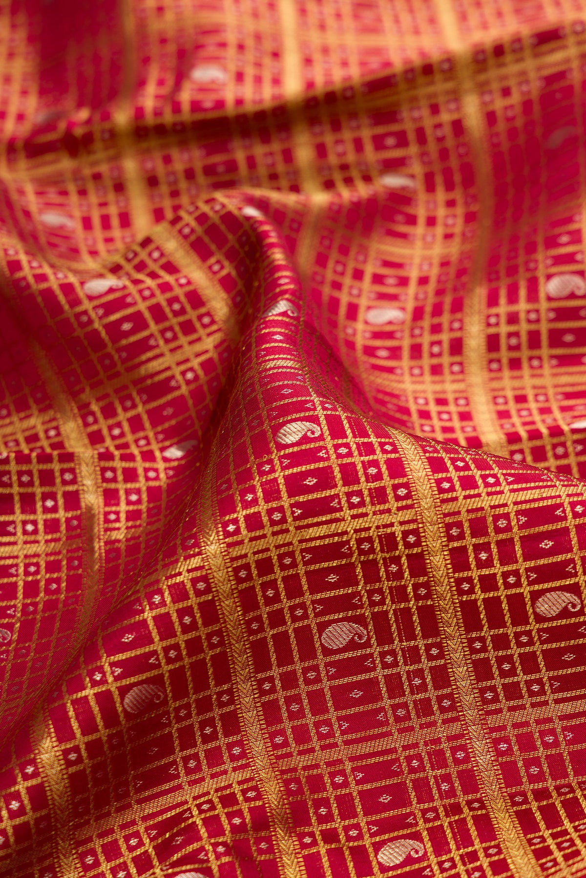Close up of Pure Silk Deep Red Dual Tone Kanchipuram Saree with Checked design on the body and Zari Border.  displaying folds