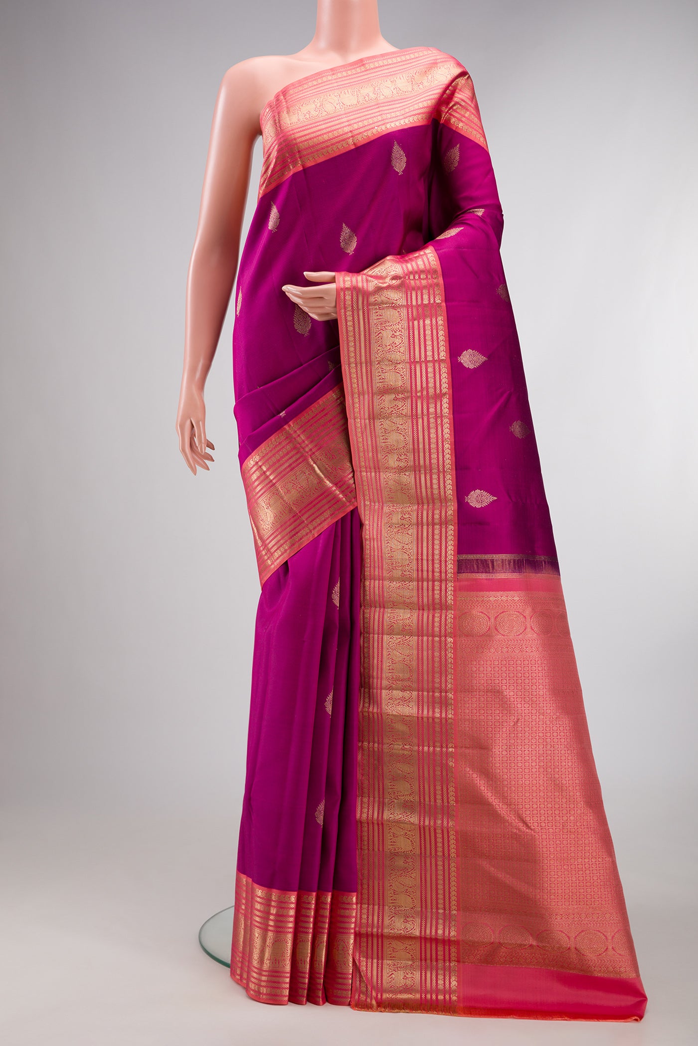 Pure Silk Magenta Kanjivaram Saree with Zari Butta on the body and Zari Border.  displayed on a mannequin
