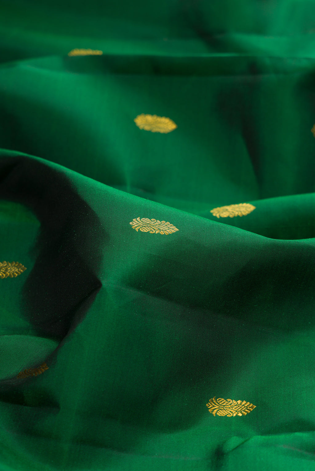 Close up of Pure Silk Bottle Green Kanjivaram Saree with Zari Butta on the body and Zari Border.  displaying folds