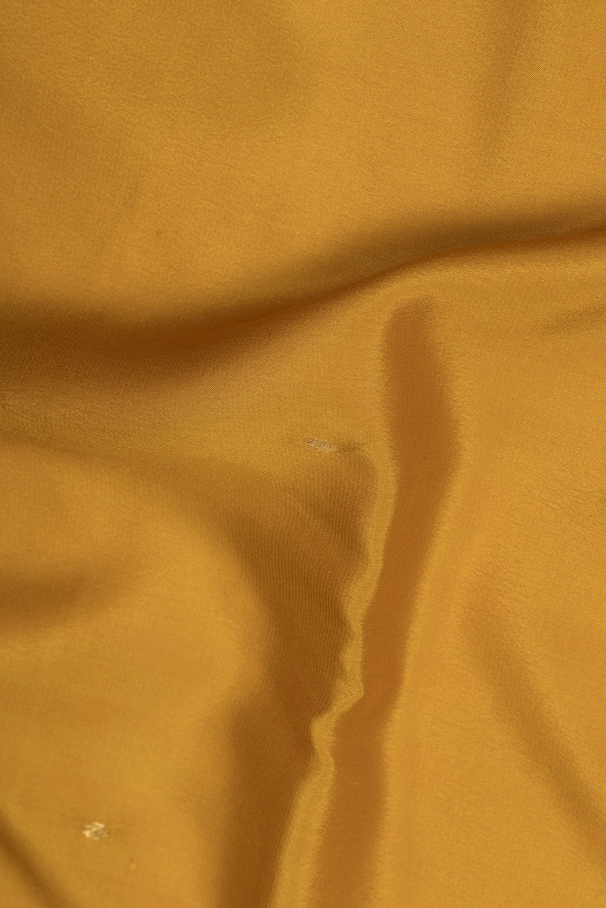 Close up of Mustard Mysore Crepe Saree with Zari Butta on the body and Zari Border.  displaying folds