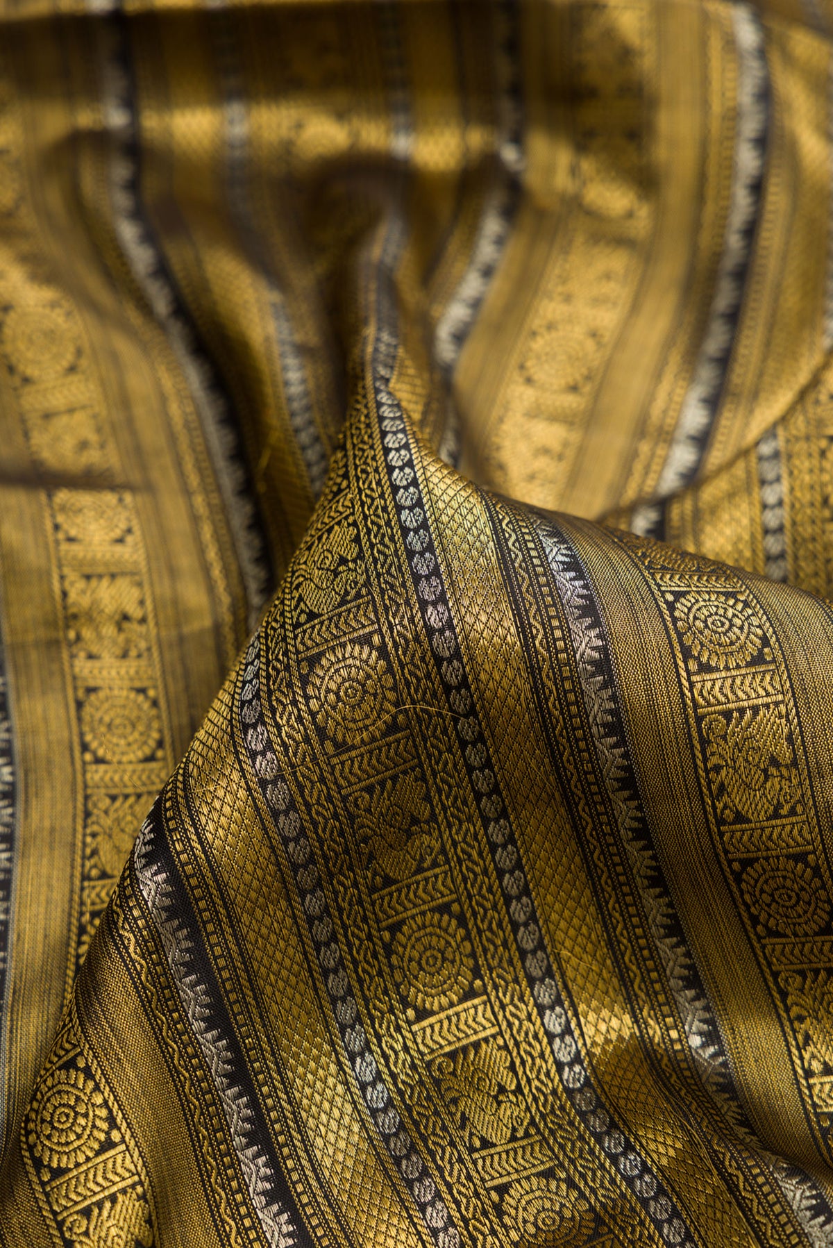 Close up of Pure Silk Black Kanchipuram Saree with Zari Brocade on the body and Fancy Border.  displaying folds