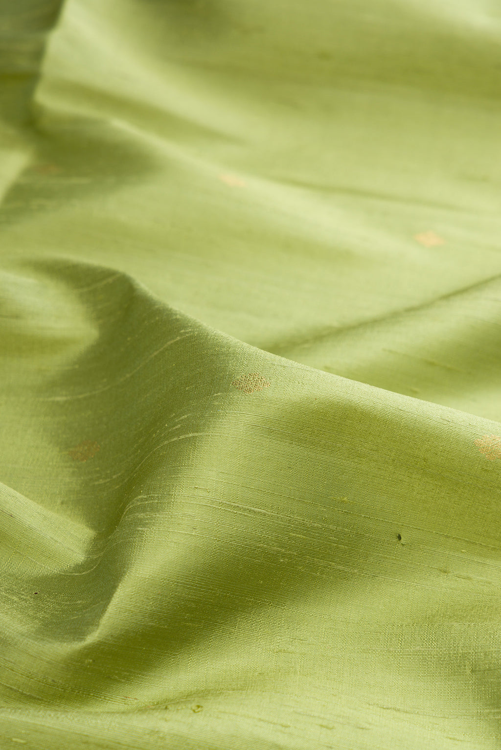 Close up of Pure Silk Pista Green Raw Saree with Zari Butta on the body and Zari Border.  displaying folds