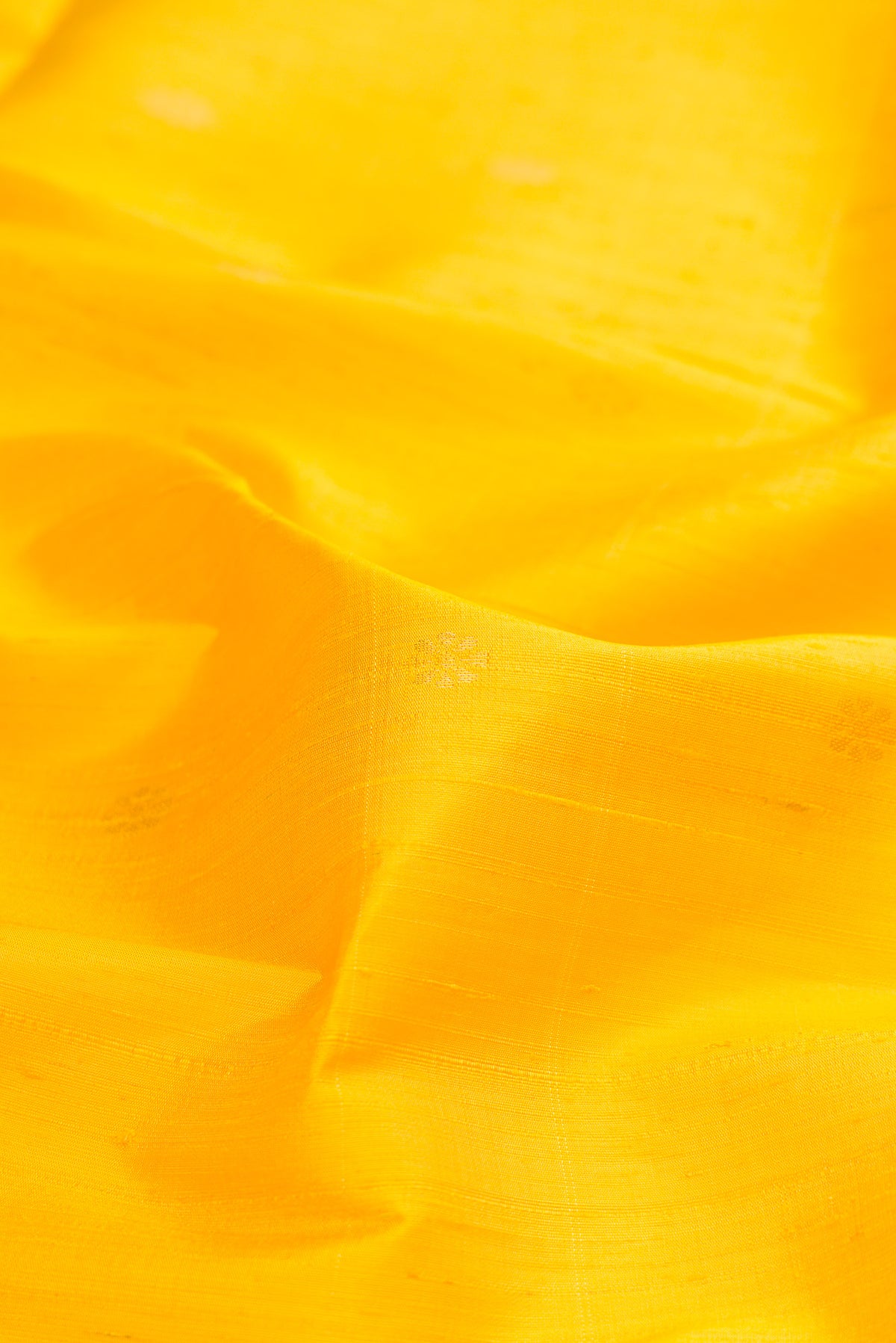 Close up of Pure Silk Yellow Raw Saree with Zari Butta on the body and Zari Border.  displaying folds