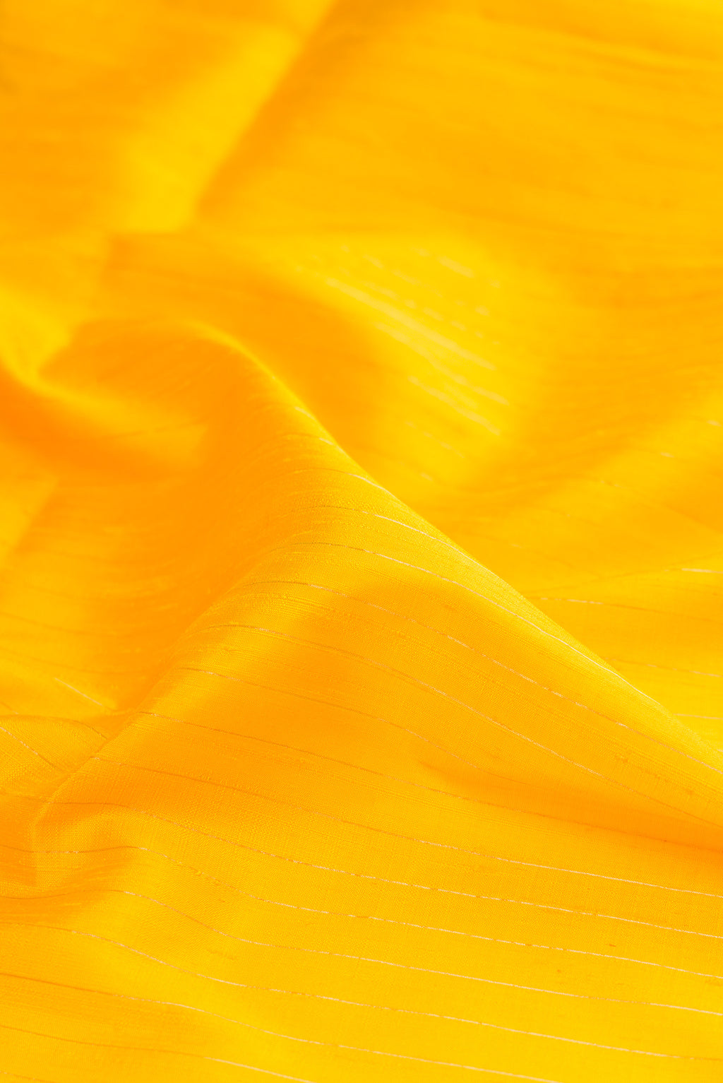 Close up of Pure Silk Yellow Raw Saree with Stripes on the body and Zari Border.  displaying folds