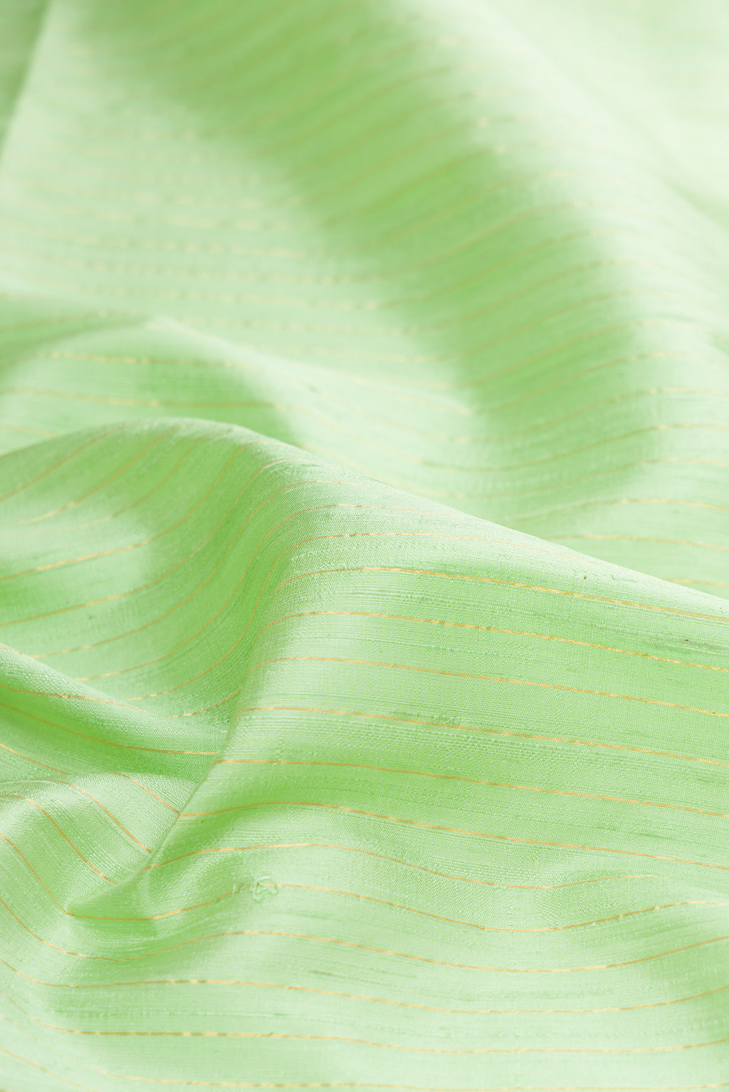 Close up of Pure Silk Pista Green Raw Saree with Stripes on the body and Zari Border.  displaying folds