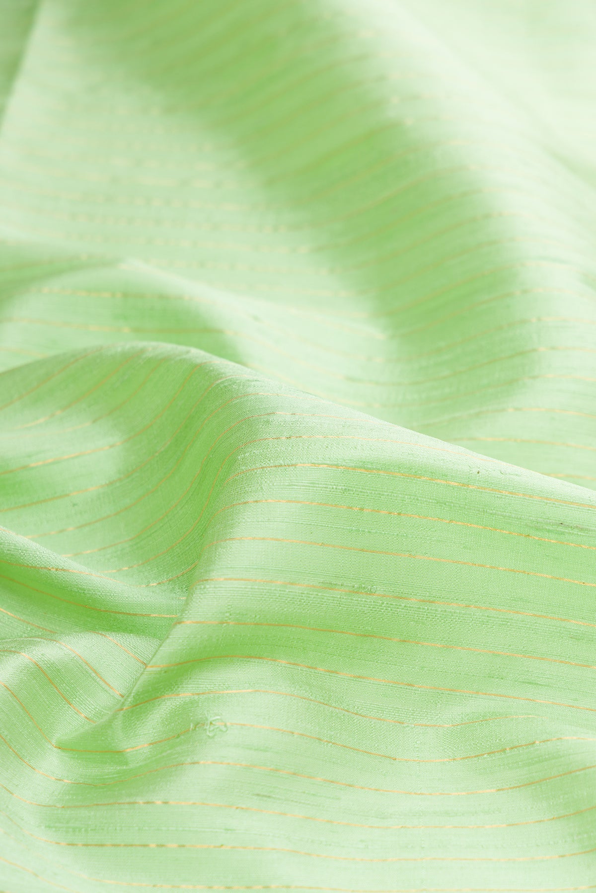 Close up of Pure Silk Pista Green Raw Saree with Stripes on the body and Zari Border.  displaying folds