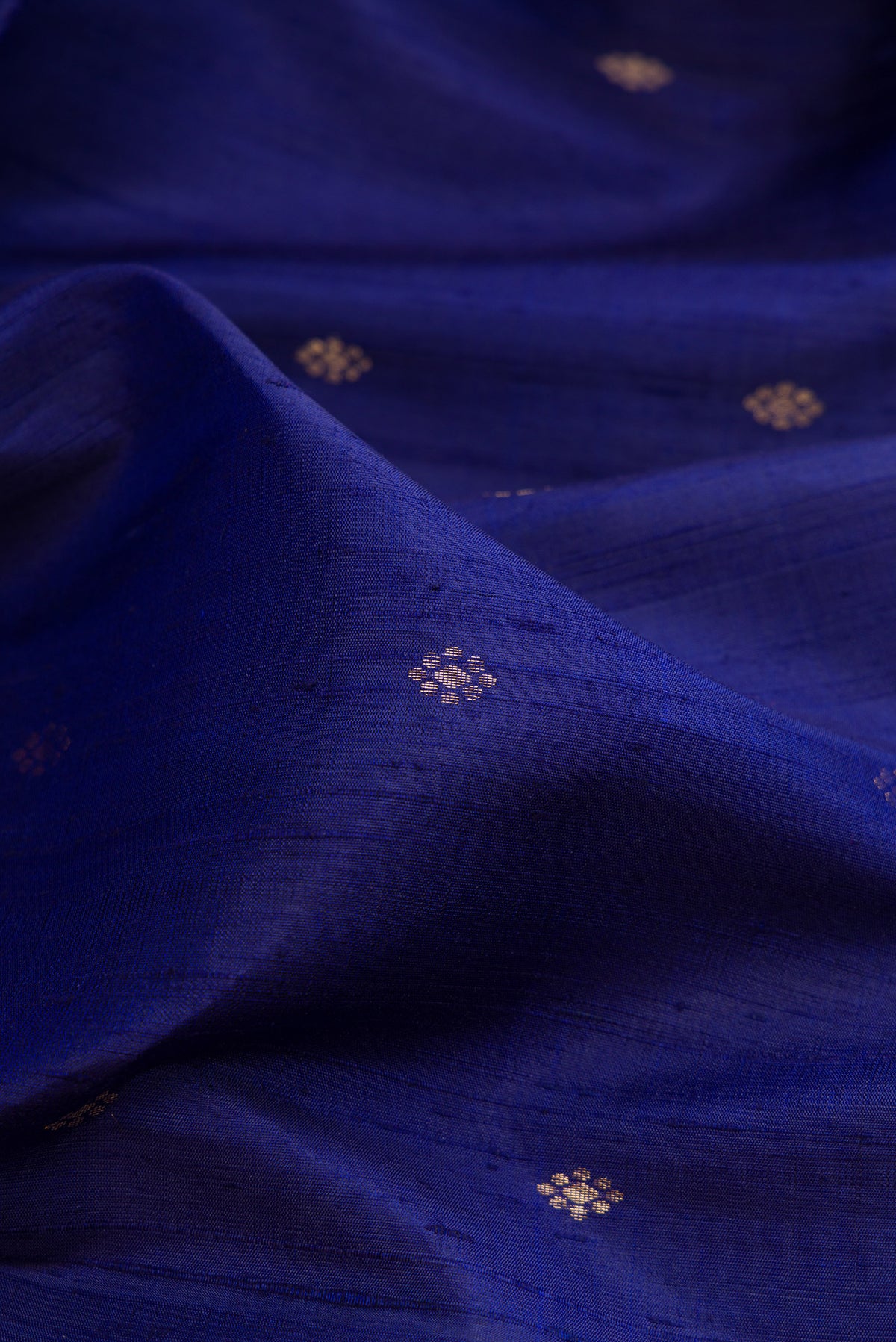 Close up of Dark Blue Raw Saree with Zari Butta on the body and Zari Border.  displaying folds