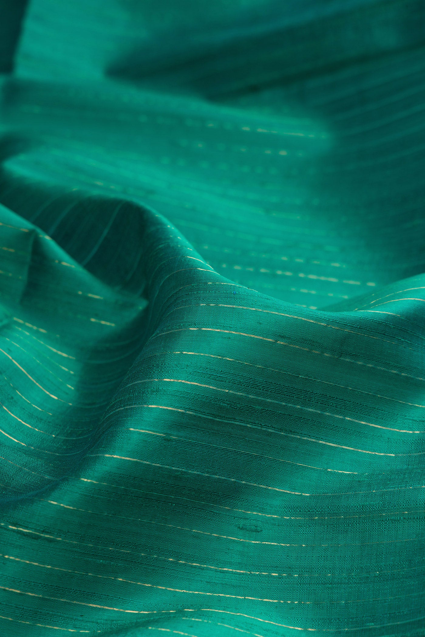 Close up of Pure Silk Teal Raw Saree with Stripes on the body and Fancy Border.  displaying folds