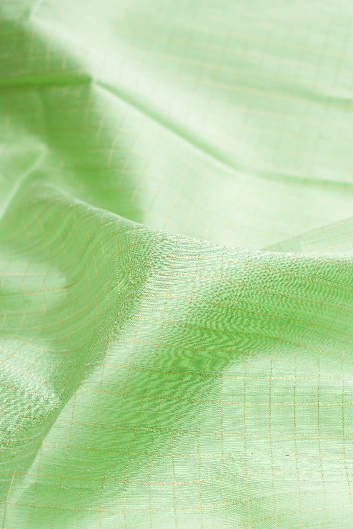 Close up of Pure Silk Pista Green Raw Saree with Checked design on the body and Fancy Border.  displaying folds