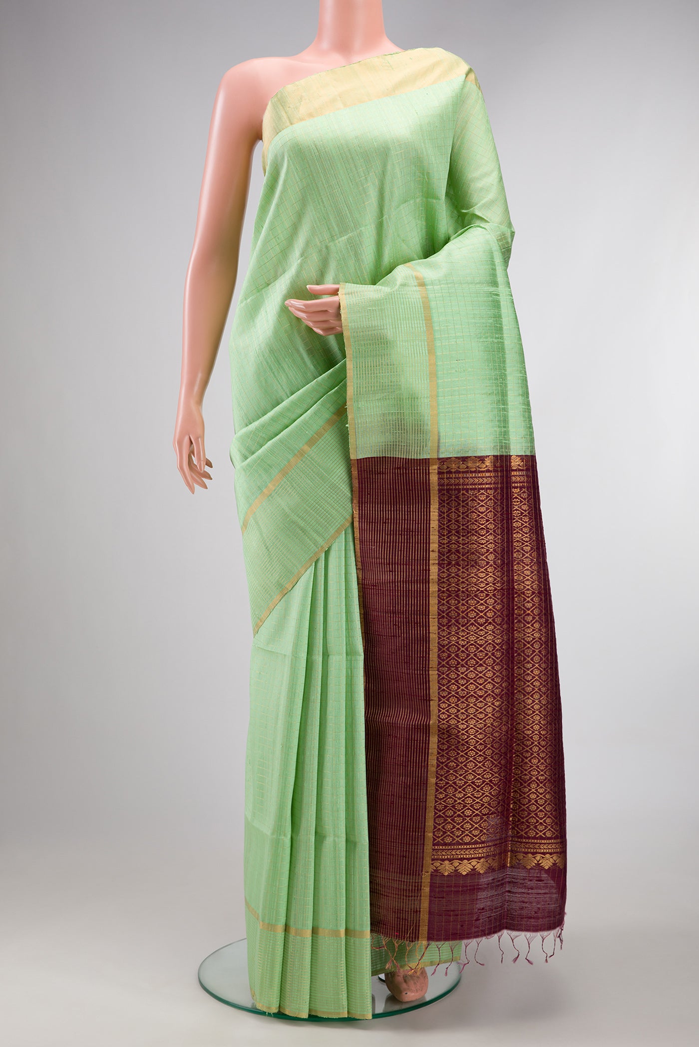 Pure Silk Pista Green Raw Saree with Checked design on the body and Fancy Border.  displayed on a mannequin