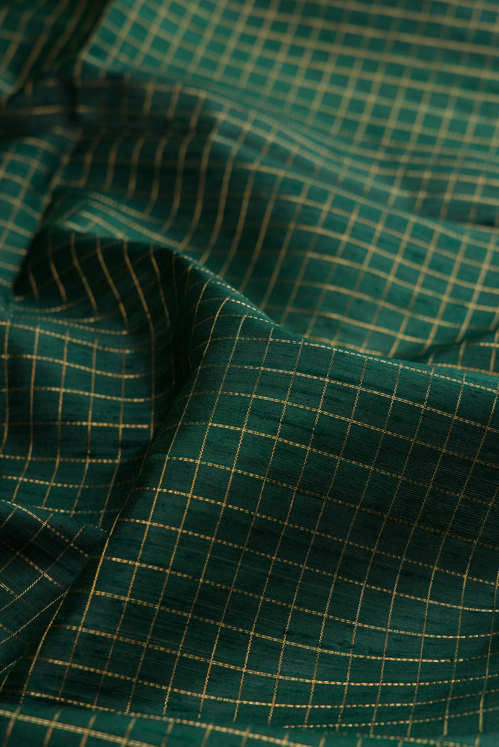 Close up of Pure Silk Bottle Green Raw Saree with Checked design on the body and Zari Border.  displaying folds