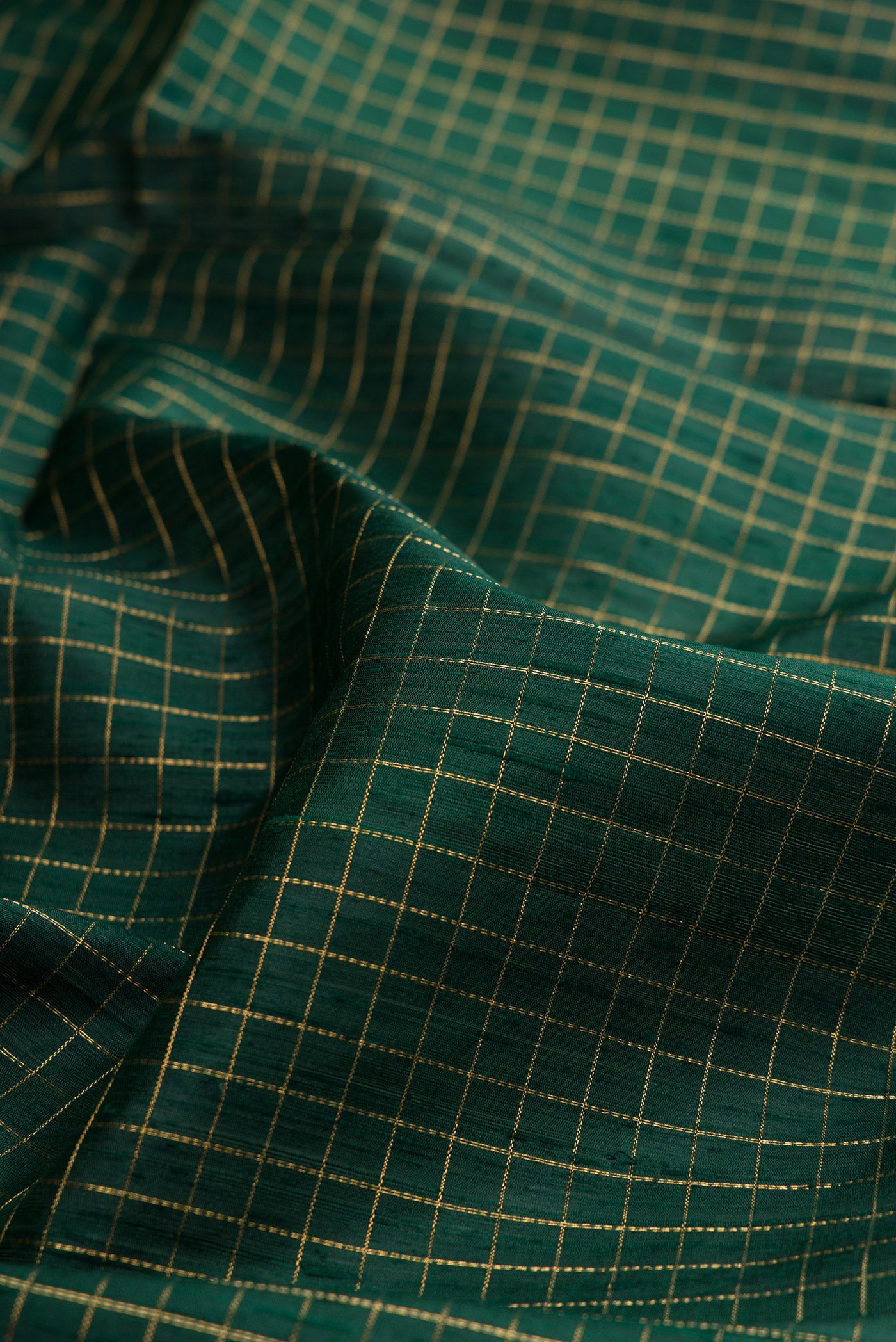 Close up of Pure Silk Bottle Green Raw Saree with Checked design on the body and Zari Border.  displaying folds