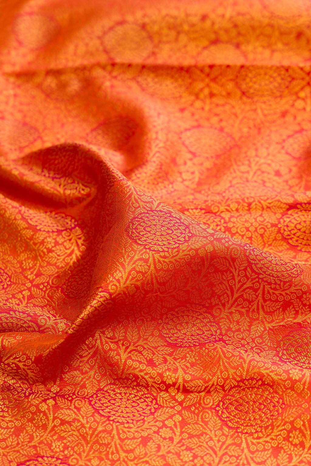 Close up of Orange Kanjivaram Silk Saree with Zari Brocade on the body and Fancy Border.  displaying folds
