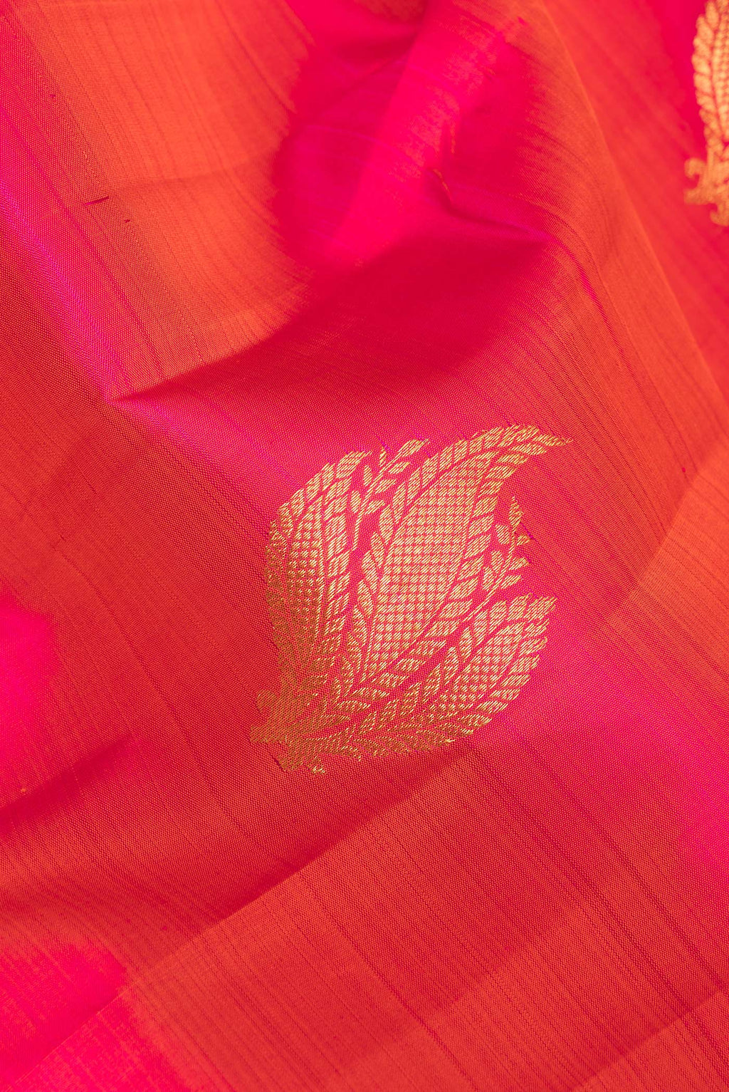Close up of Pure Silk Orange Dual Tone Kanchipuram Saree with Zari Butta on the body and Zari Border.  displaying folds