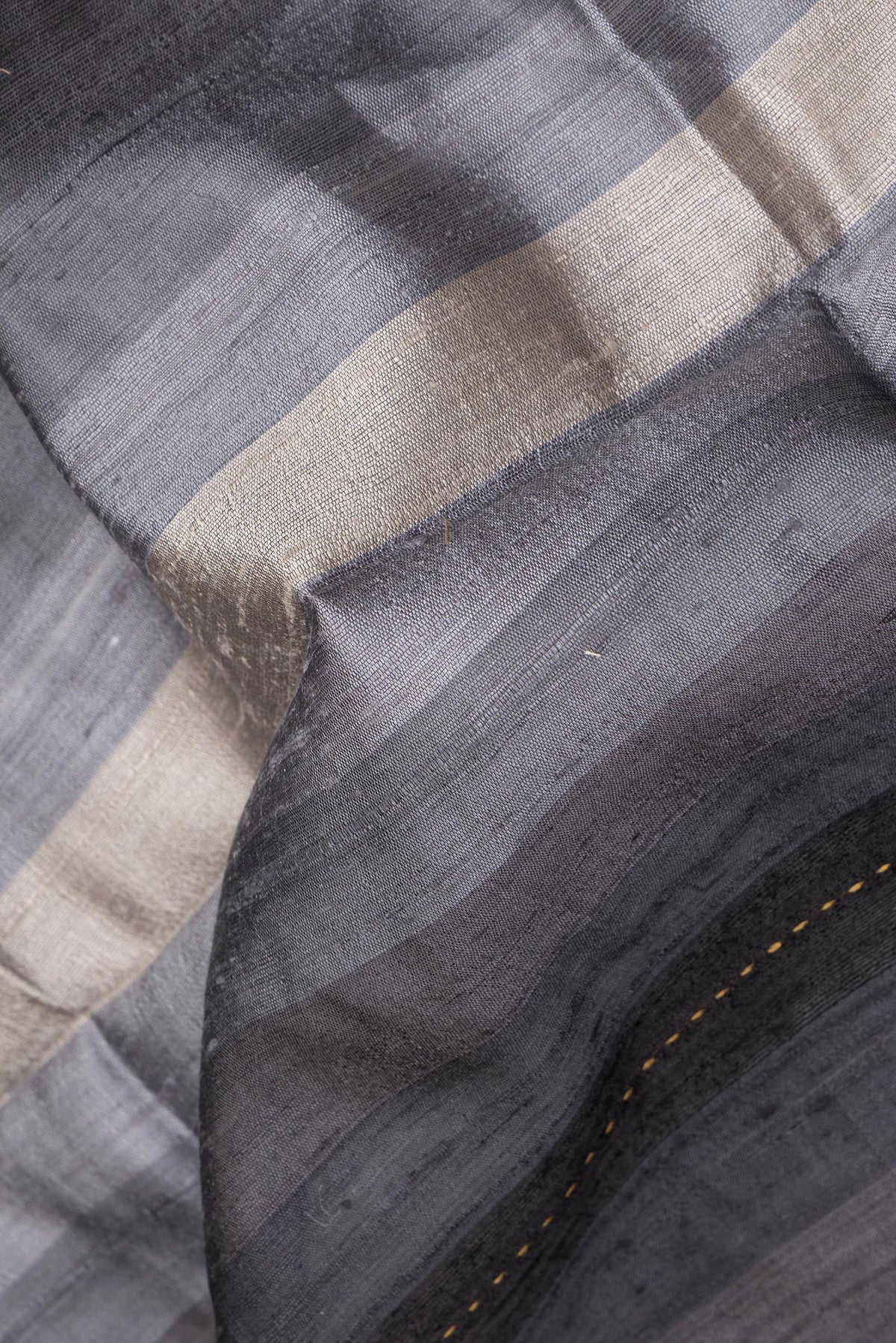 Close up of Pure Silk Grey Dual Tone Tussar Saree with Stripes on the body and Embroidery Border.  displaying folds