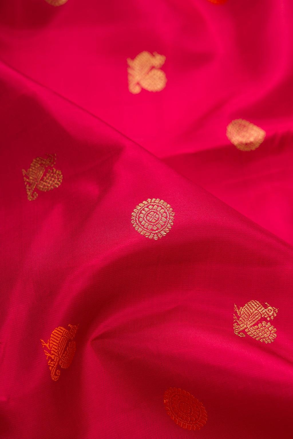 Close up of Pure Silk Pure Zari Deep Red Kanjivaram Saree with Zari And Thread Butta on the body and Zari Border.  displaying folds
