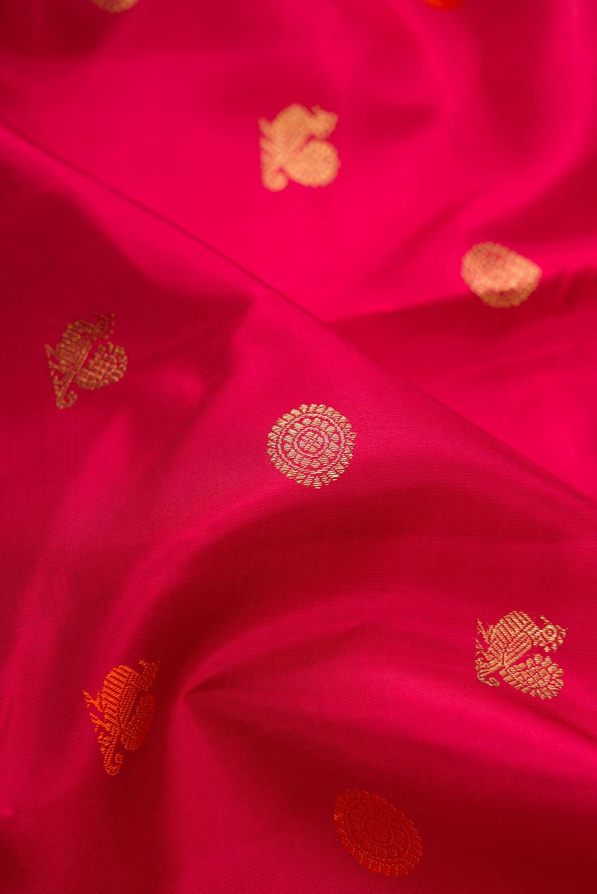 Close up of Pure Silk Pure Zari Deep Red Kanjivaram Saree with Zari And Thread Butta on the body and Zari Border.  displaying folds