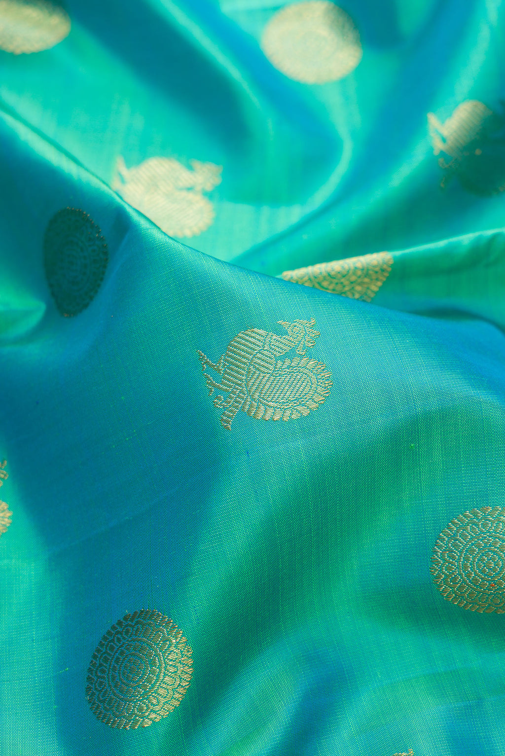 Close up of Pure Silk Pure Zari Sea Green Kanjivaram Saree with Zari Butta on the body and Temple Border.  displaying folds