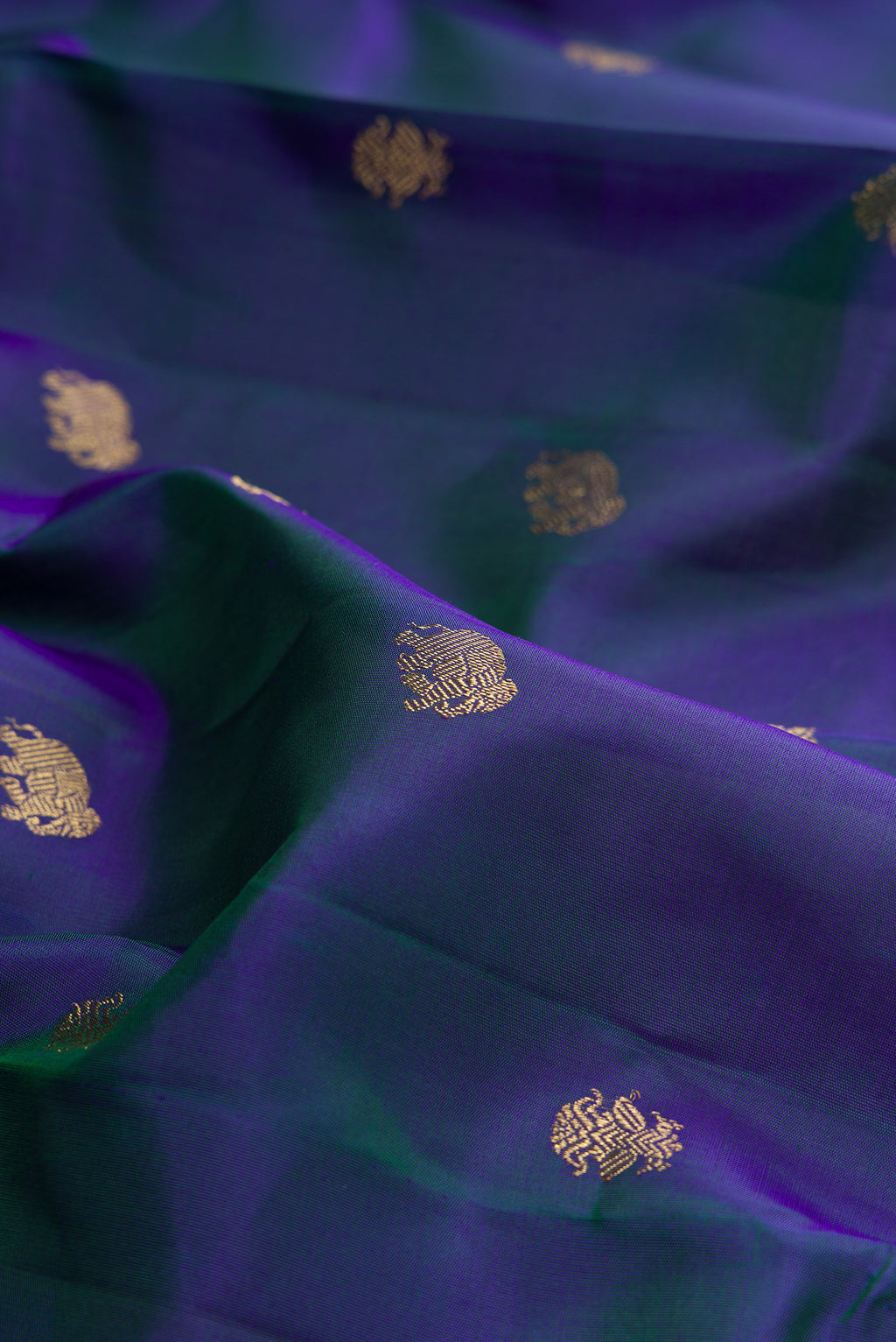 Close up of Pure Silk Pure Zari Peacock Blue Dual Tone Kanchipuram Saree with Zari Butta on the body and Zari Border.  displaying folds