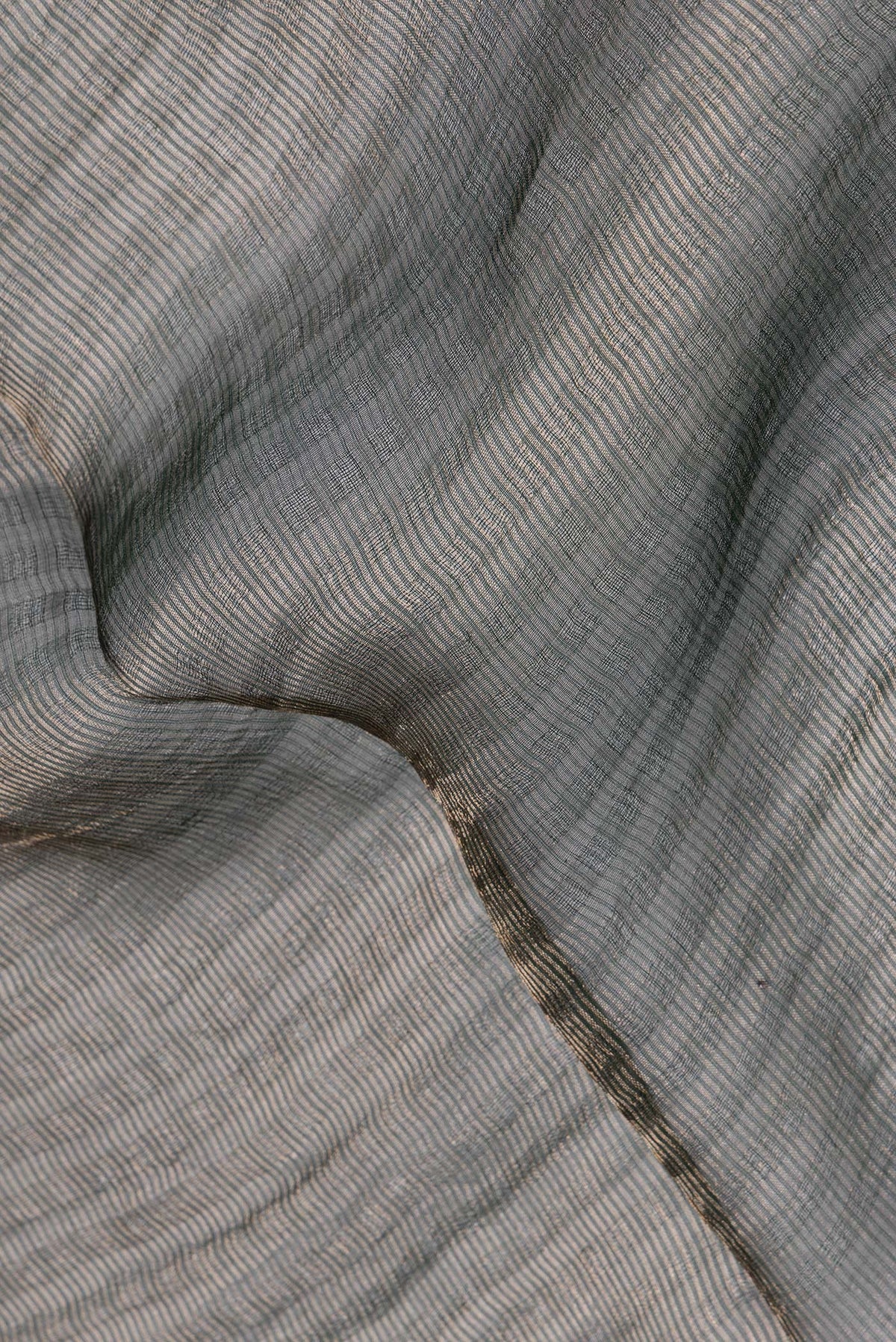 Close up of Pure Silk Green Dual Tone Tussar Saree with Stripes on the body and Sequin Border.  displaying folds