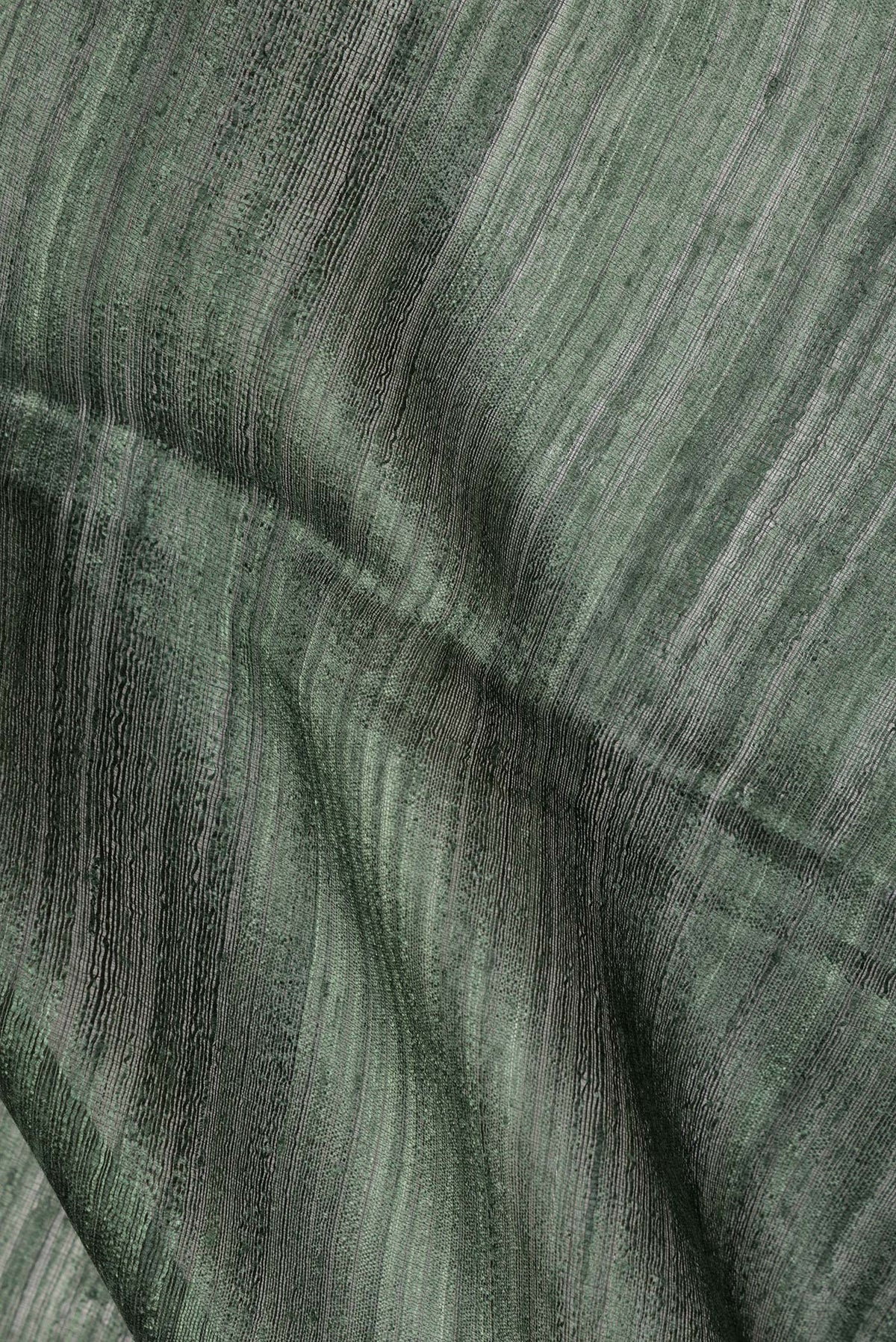 Close up of Bottle Green Tussar Saree with Zari Butta on the body and Fancy Border.  displaying folds
