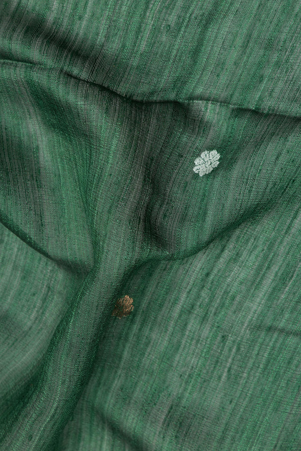 Close up of Pure Silk Bottle Green Tussar Saree with Zari Butta on the body and Fancy Border.  displaying folds