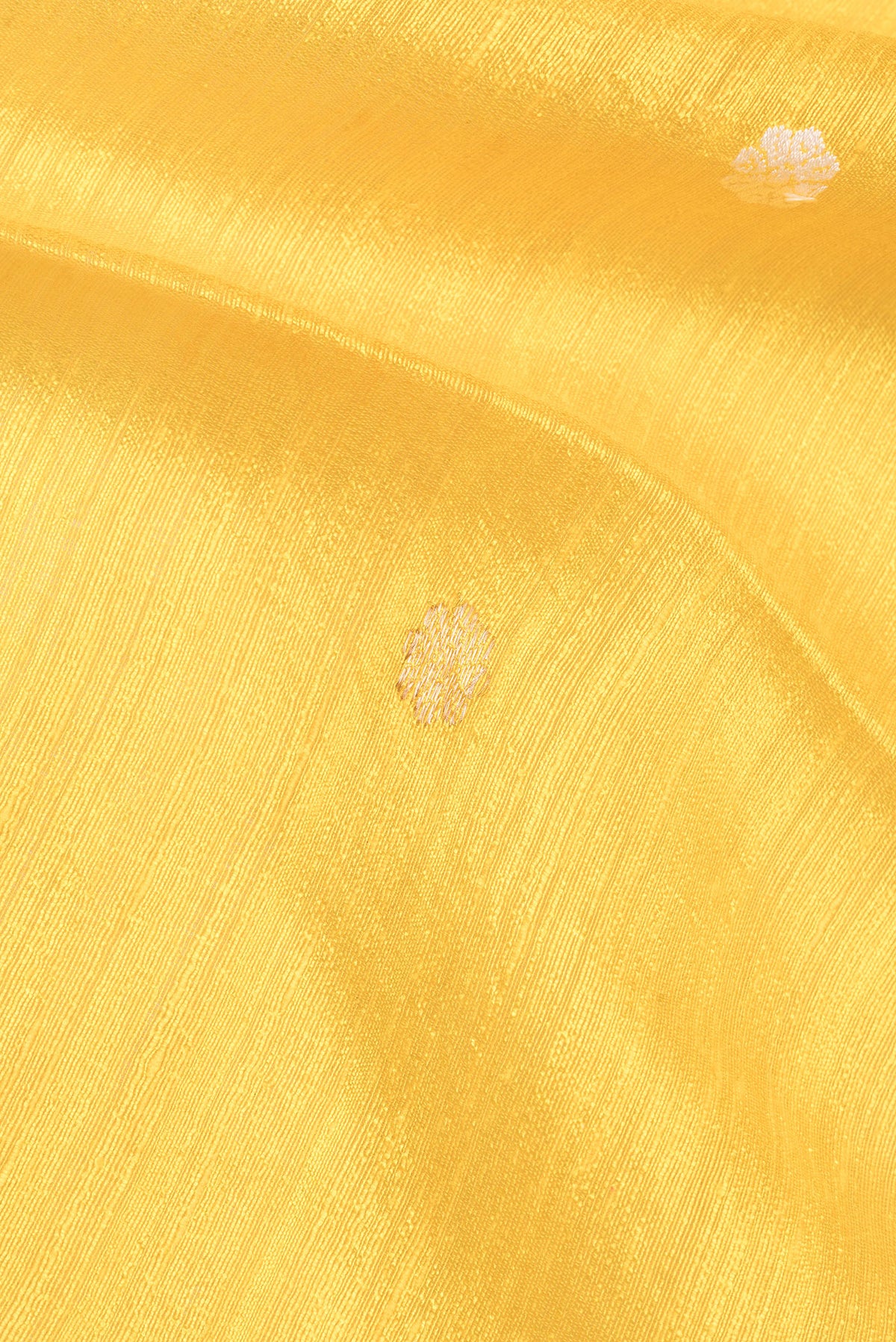 Close up of Pure Silk Lemon Yellow Tussar Saree with Zari Butta on the body and Fancy Border.  displaying folds