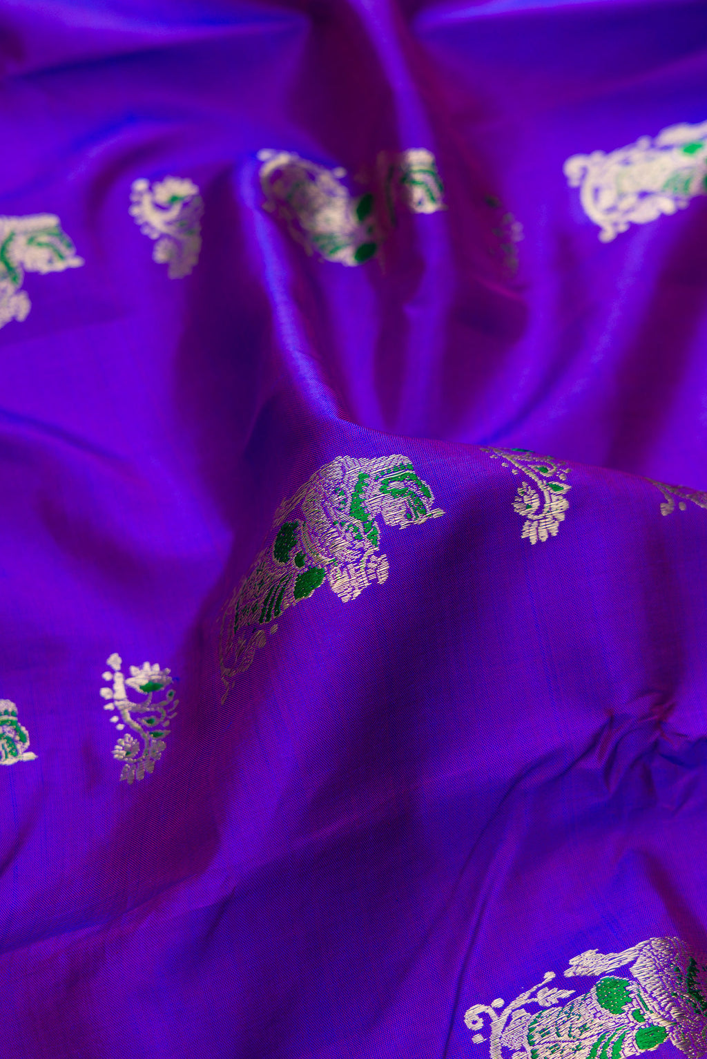 Close up of Pure Silk Purple Dual Tone Baluchari Saree with Zari And Thread Butta on the body and Fancy Border.  displaying folds