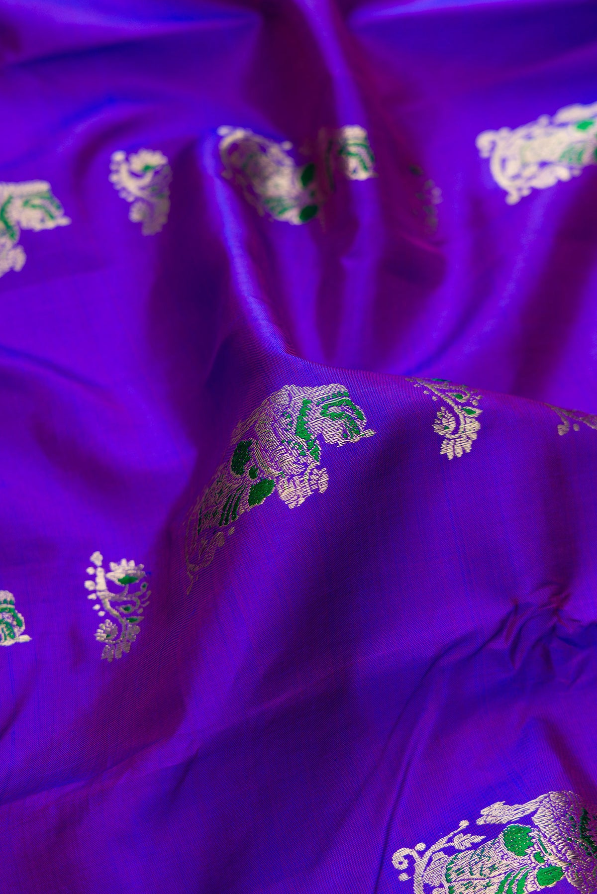Close up of Pure Silk Purple Dual Tone Baluchari Saree with Zari And Thread Butta on the body and Fancy Border.  displaying folds
