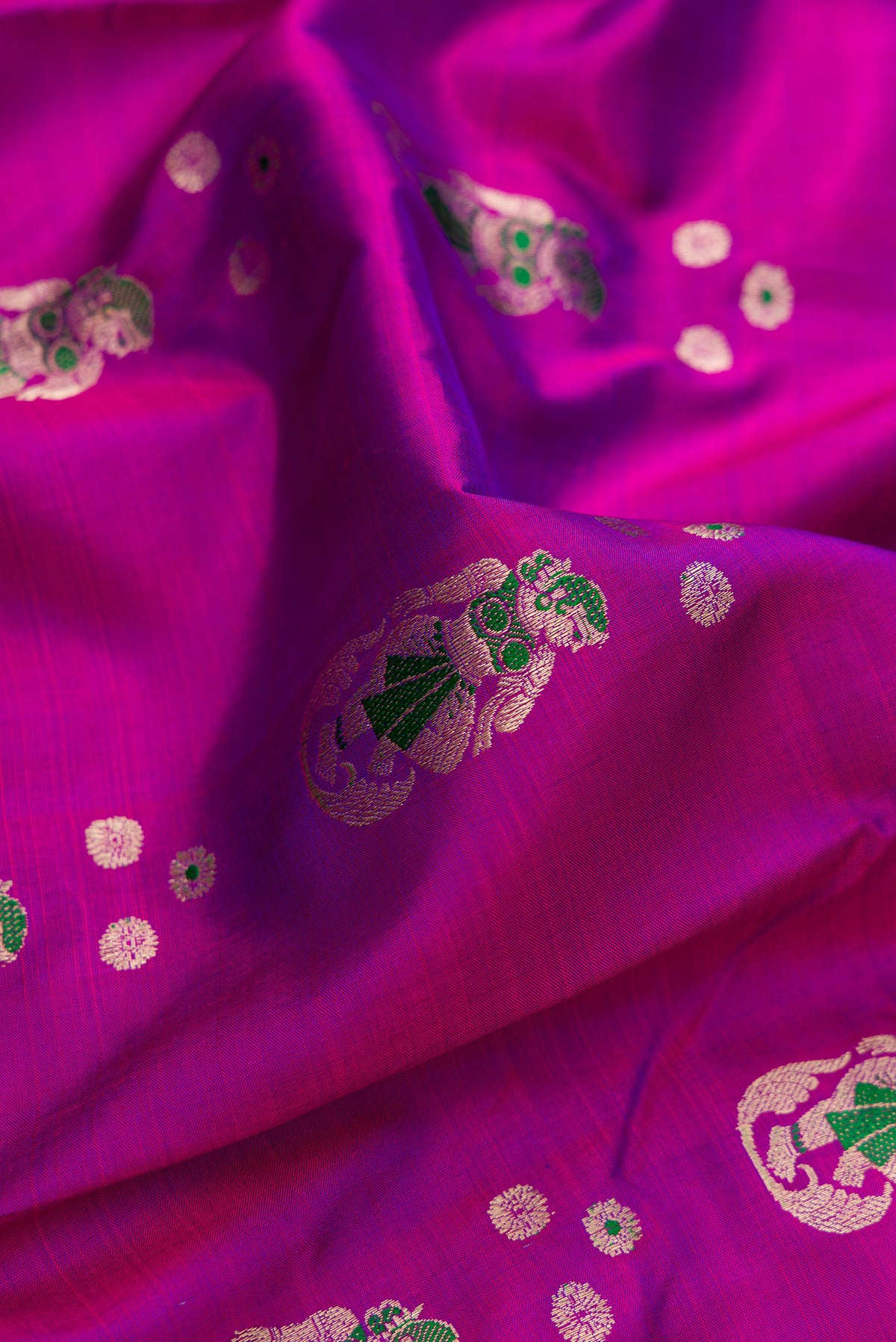 Close up of Pure Silk Magenta Dual Tone Baluchari Saree with Zari And Thread Butta on the body and Fancy Border.  displaying folds