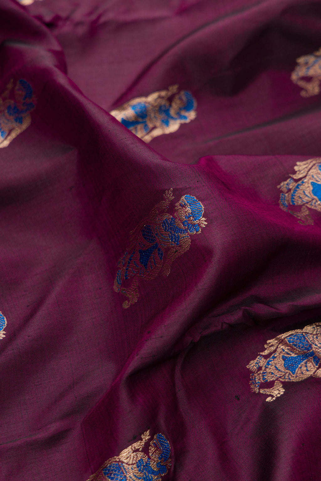 Close up of Pure Silk Burgundy Dual Tone Baluchari Saree with Zari And Thread Butta on the body and Fancy Border.  displaying folds