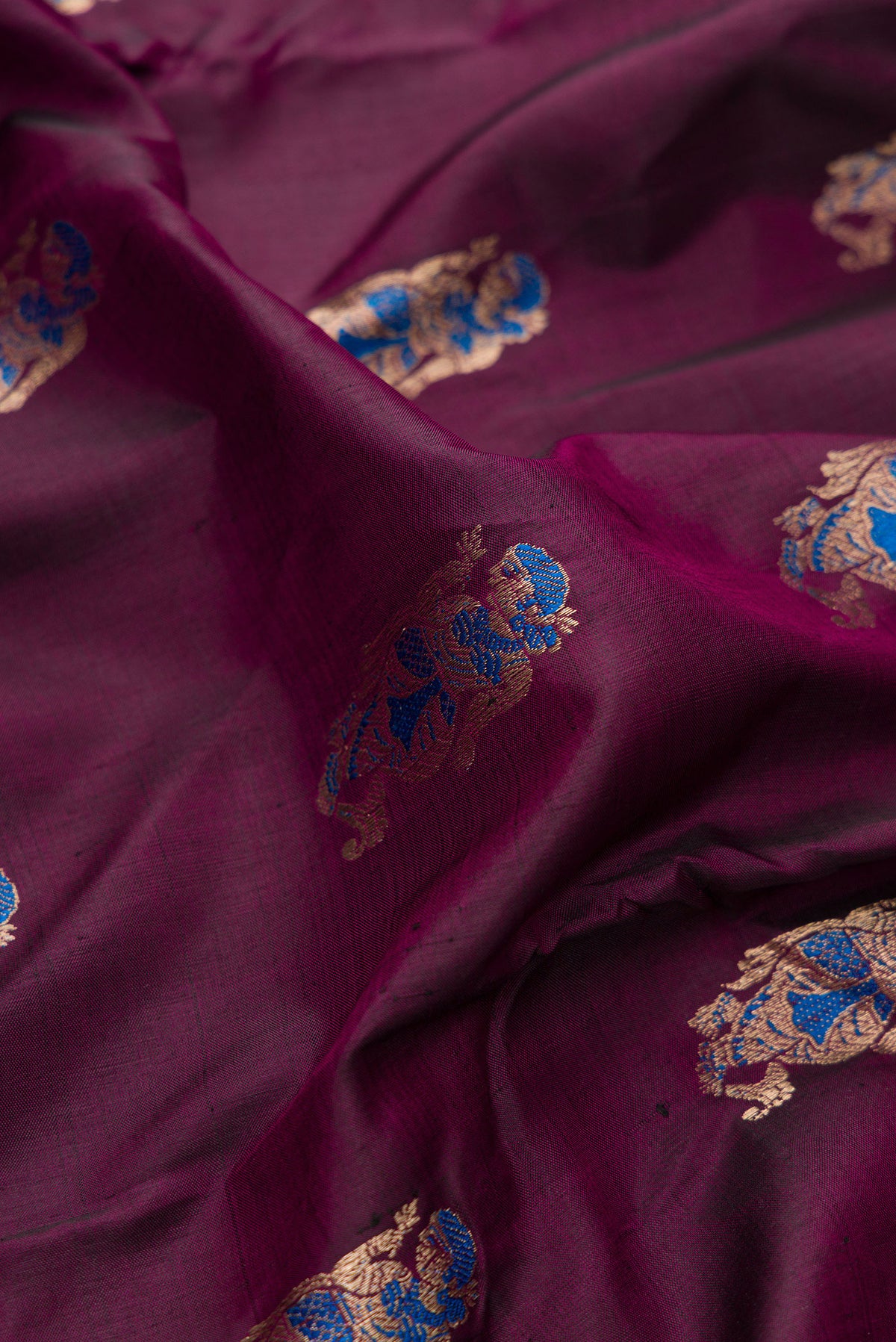 Close up of Pure Silk Burgundy Dual Tone Baluchari Saree with Zari And Thread Butta on the body and Fancy Border.  displaying folds