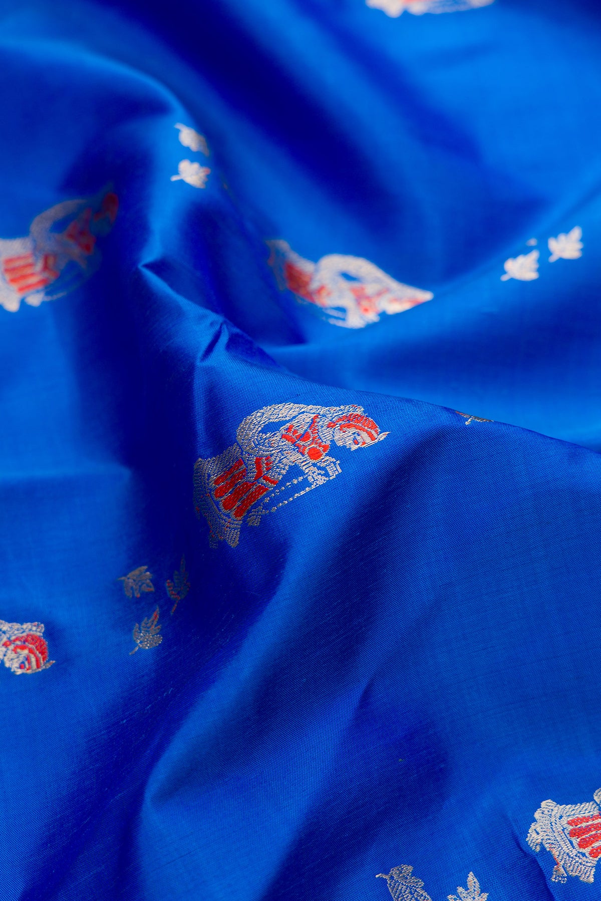 Close up of Pure Silk Royal Blue Baluchari Saree with Zari And Thread Butta on the body and Zari Border.  displaying folds